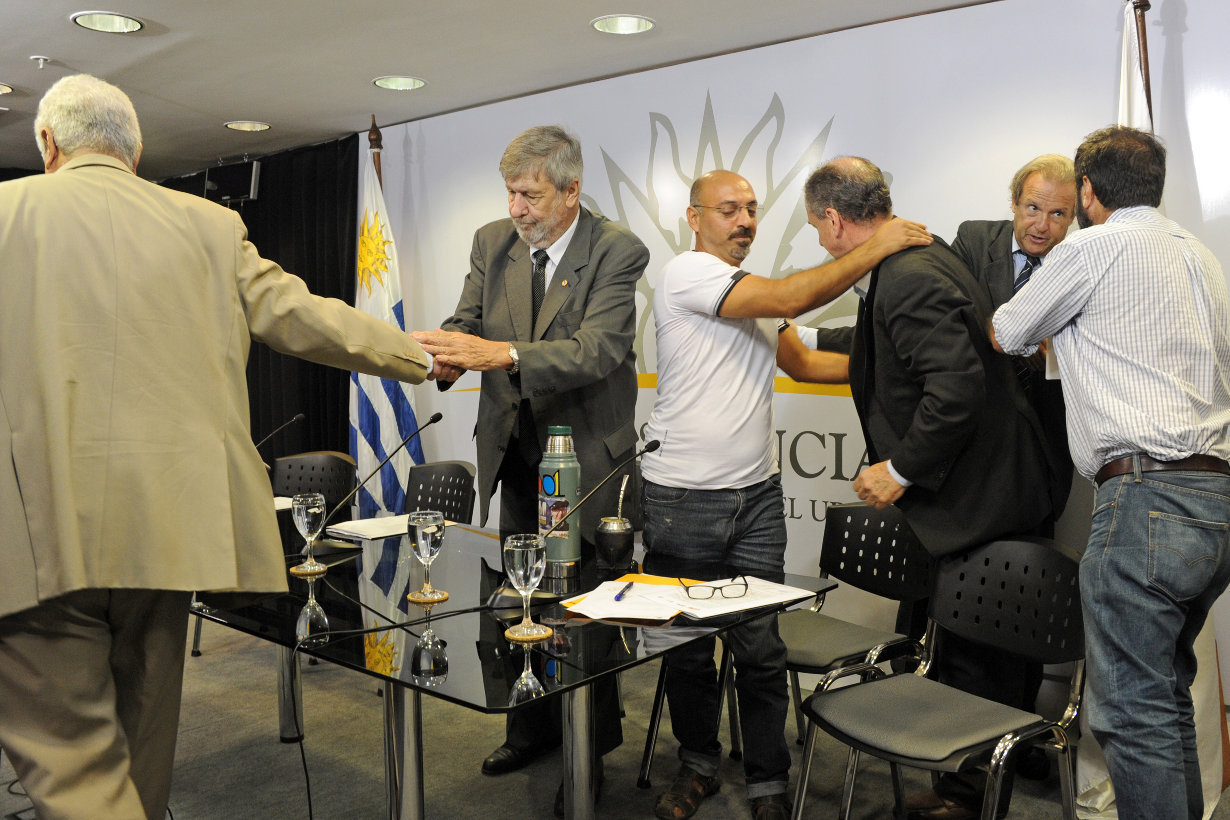 Representantes de los trabajadores, empresarios y gobierno, se saludan luego de acordar la suspensión de queja ante la OIT: