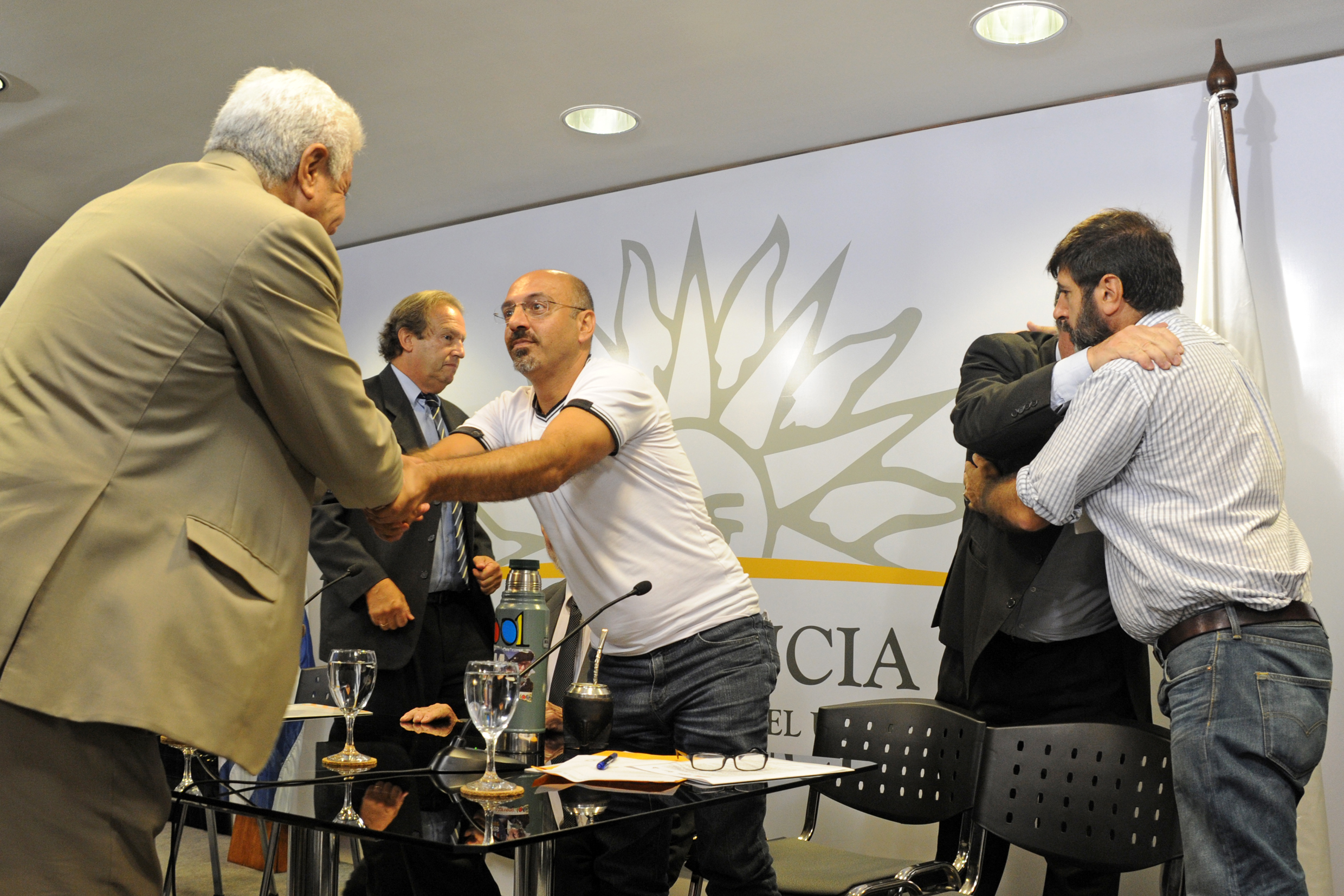Representantes de los trabajadores, empresarios y gobierno, se saludan luego de acordar la suspensión de queja ante la OIT: