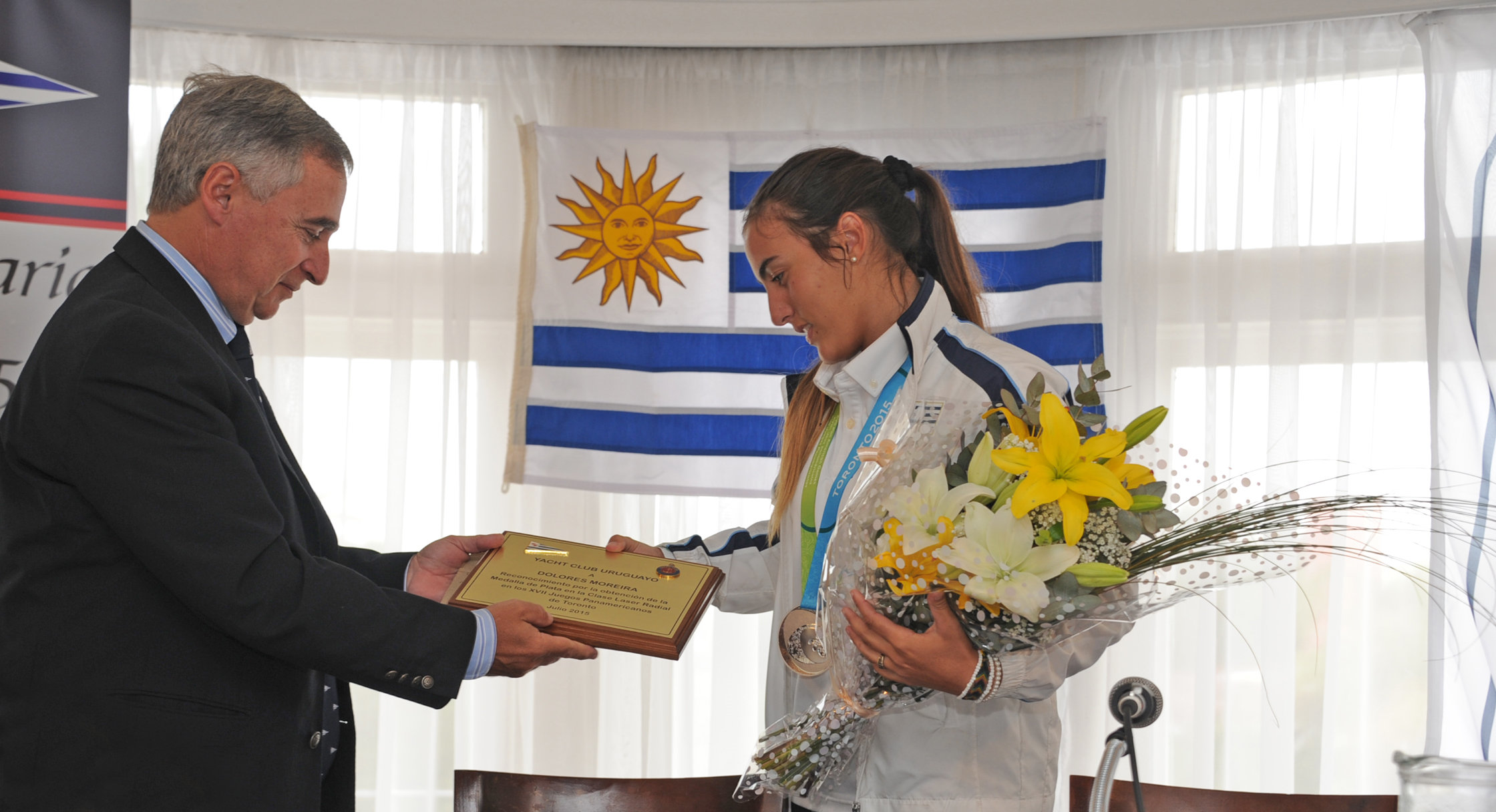 Sergio Pérez, representante del Yacht Club de Montevideo, entregando una plaqueta en reconocimiento a Dolores Moreira