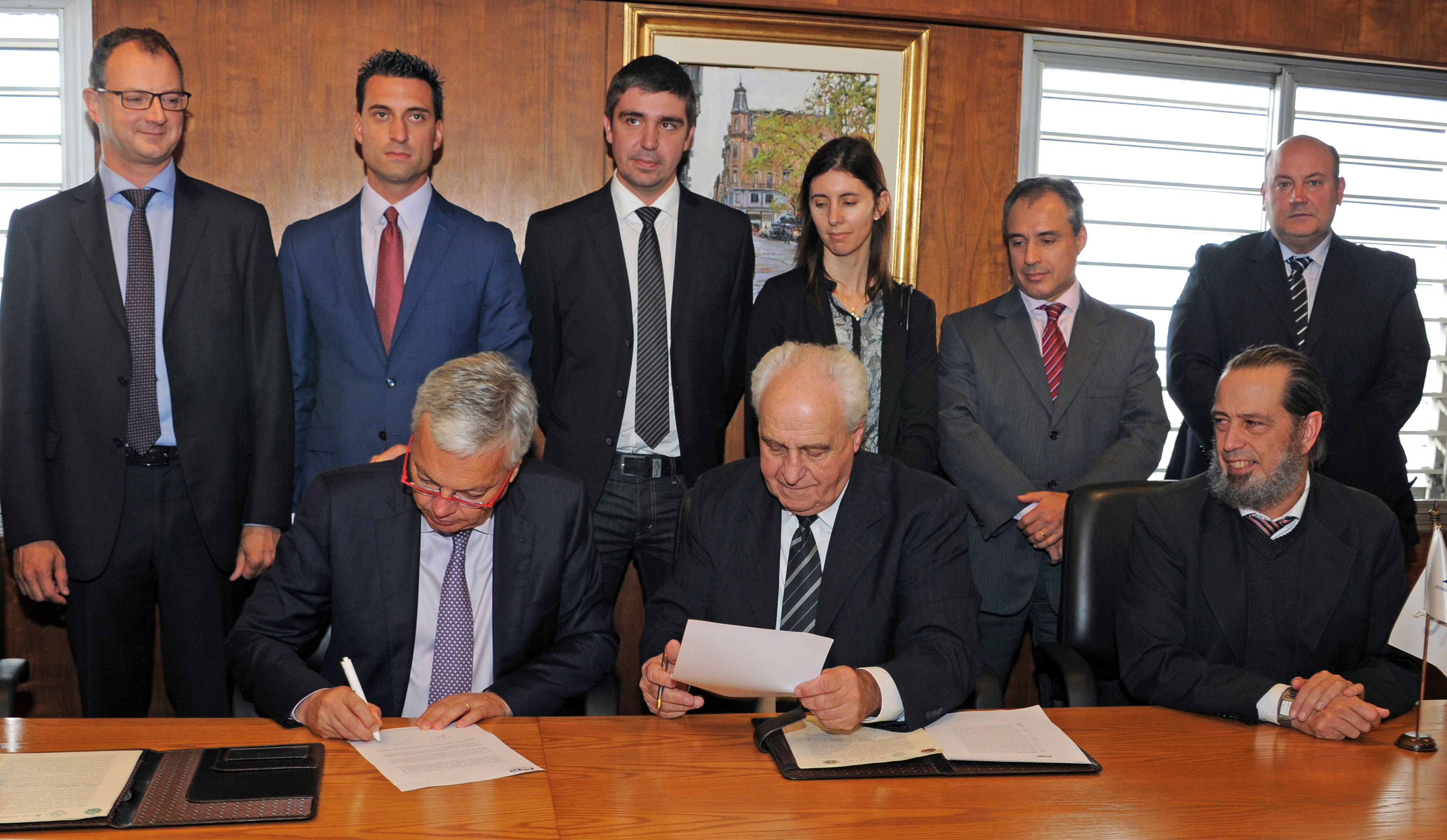 Firma de contrato entre Víctor Rossi y Didier Reynders