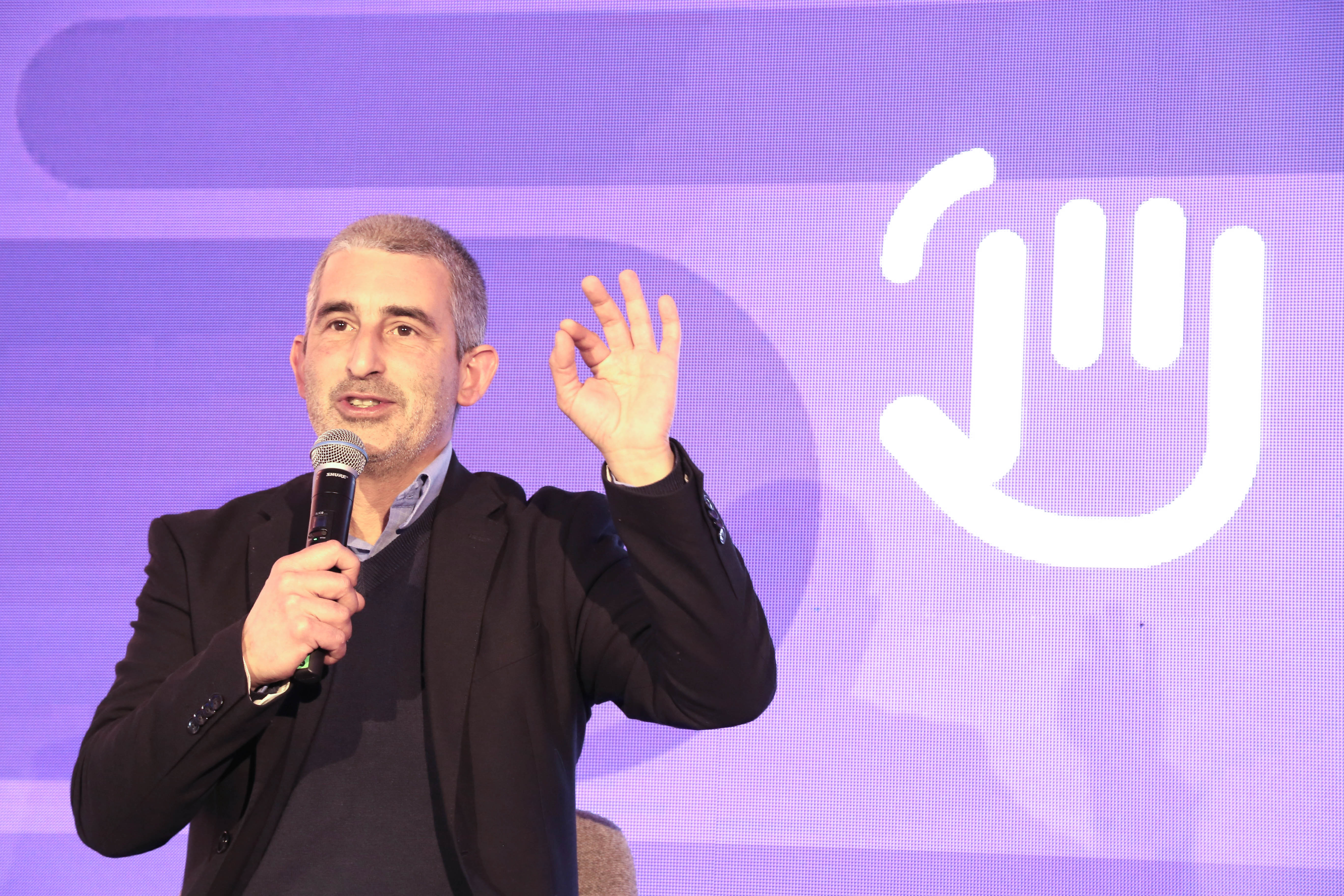 Presidente de la ANEP diserta parado con micrófono en escenario. Atrás, cartel violeta con logo del evento.