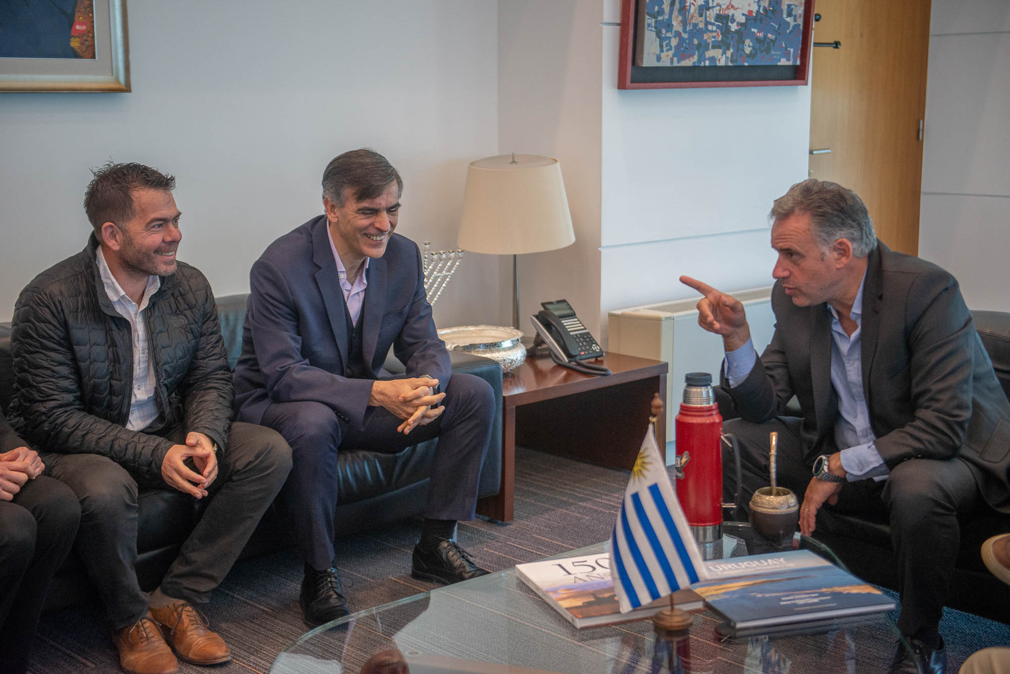 Orsi dialoga con dos integrantes de las cámaras empresariales sentados en sillones en el despacho presidencial