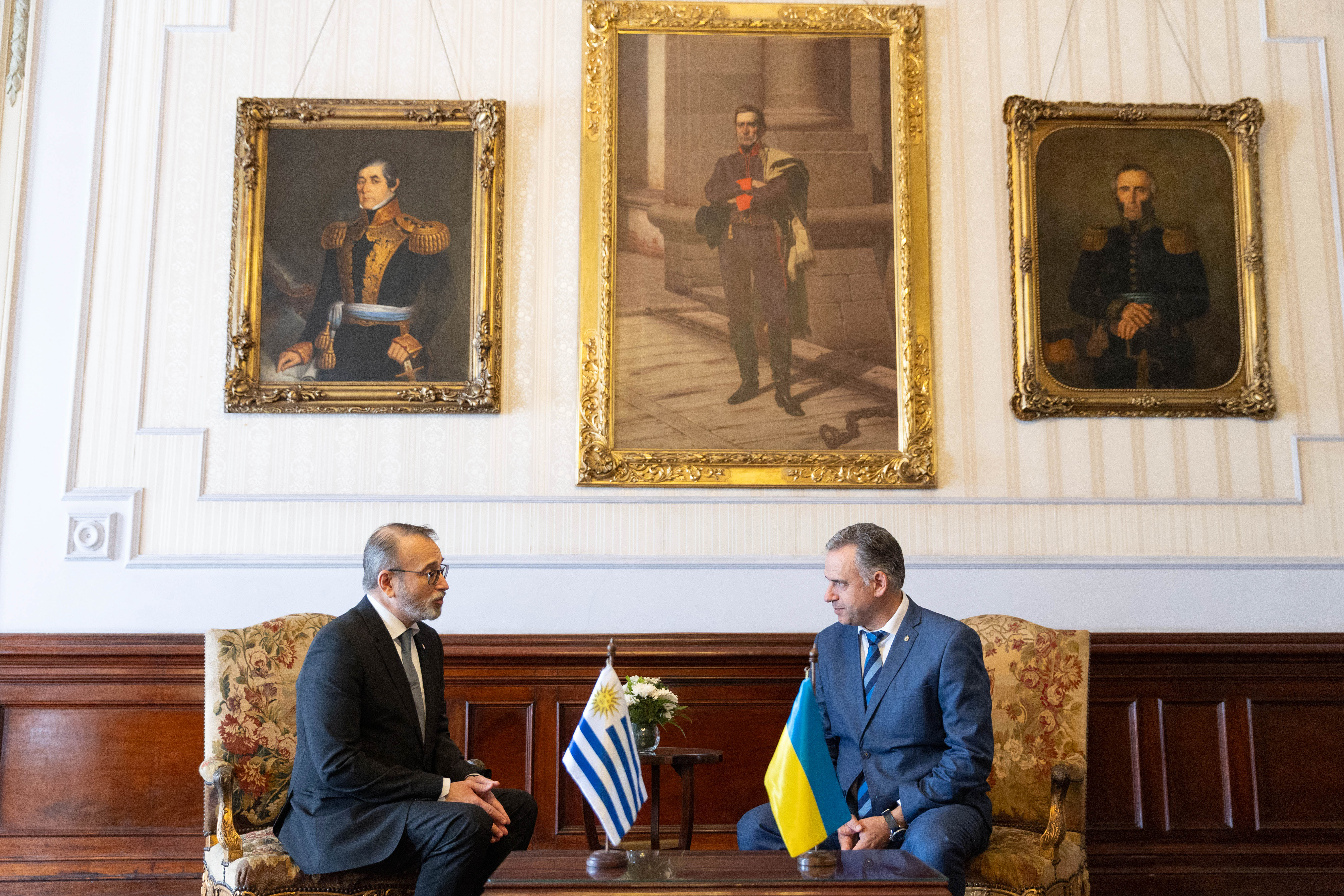 Orsi y el embajador de Ucrania sentados en sillones dialogan entre sí. Atrás se observan cuadros de próceres uruguayos.