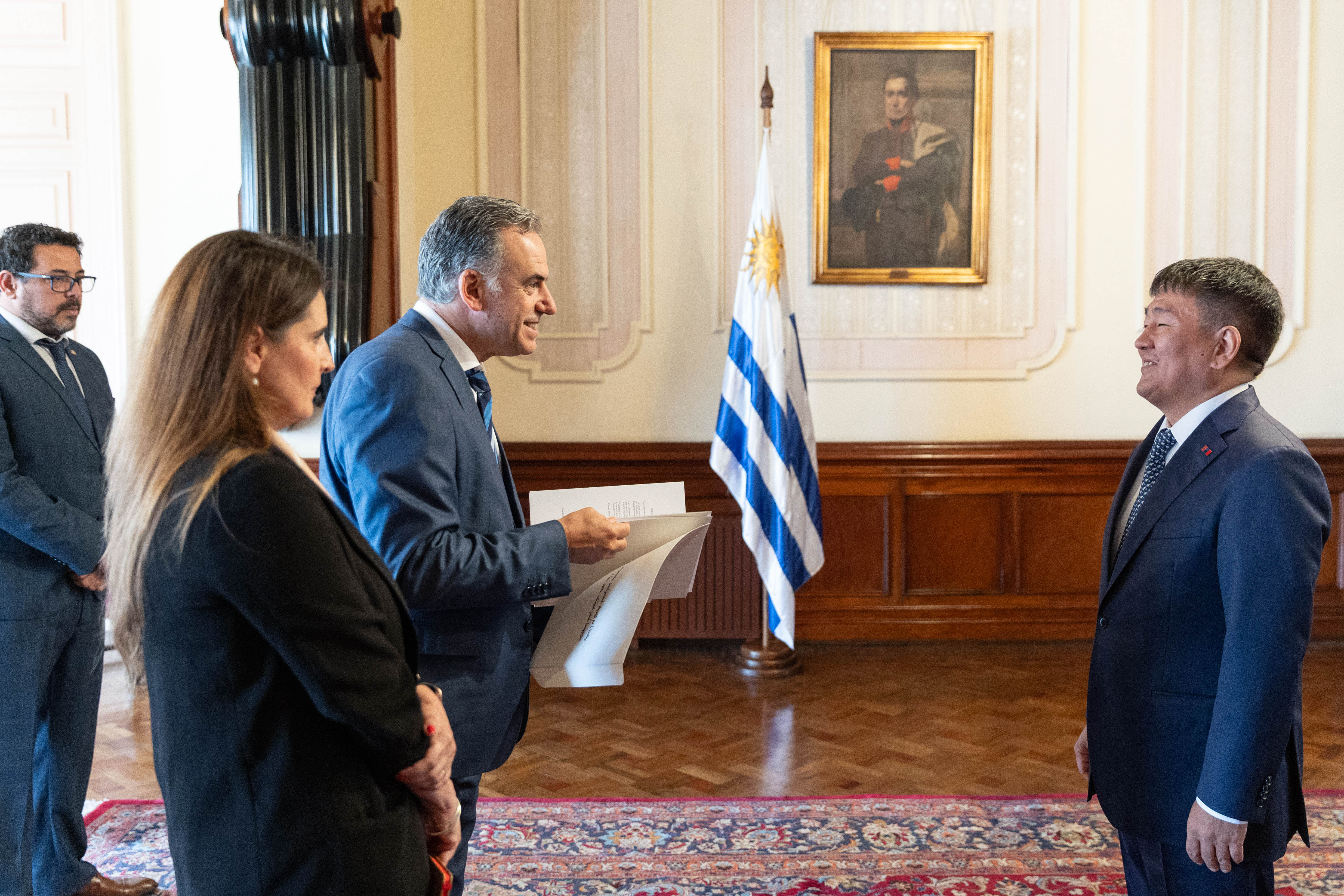 Orsi dialoga con el embajador de Mongolia mientras sostiene en sus manos las cartas credenciales de la autoridad.