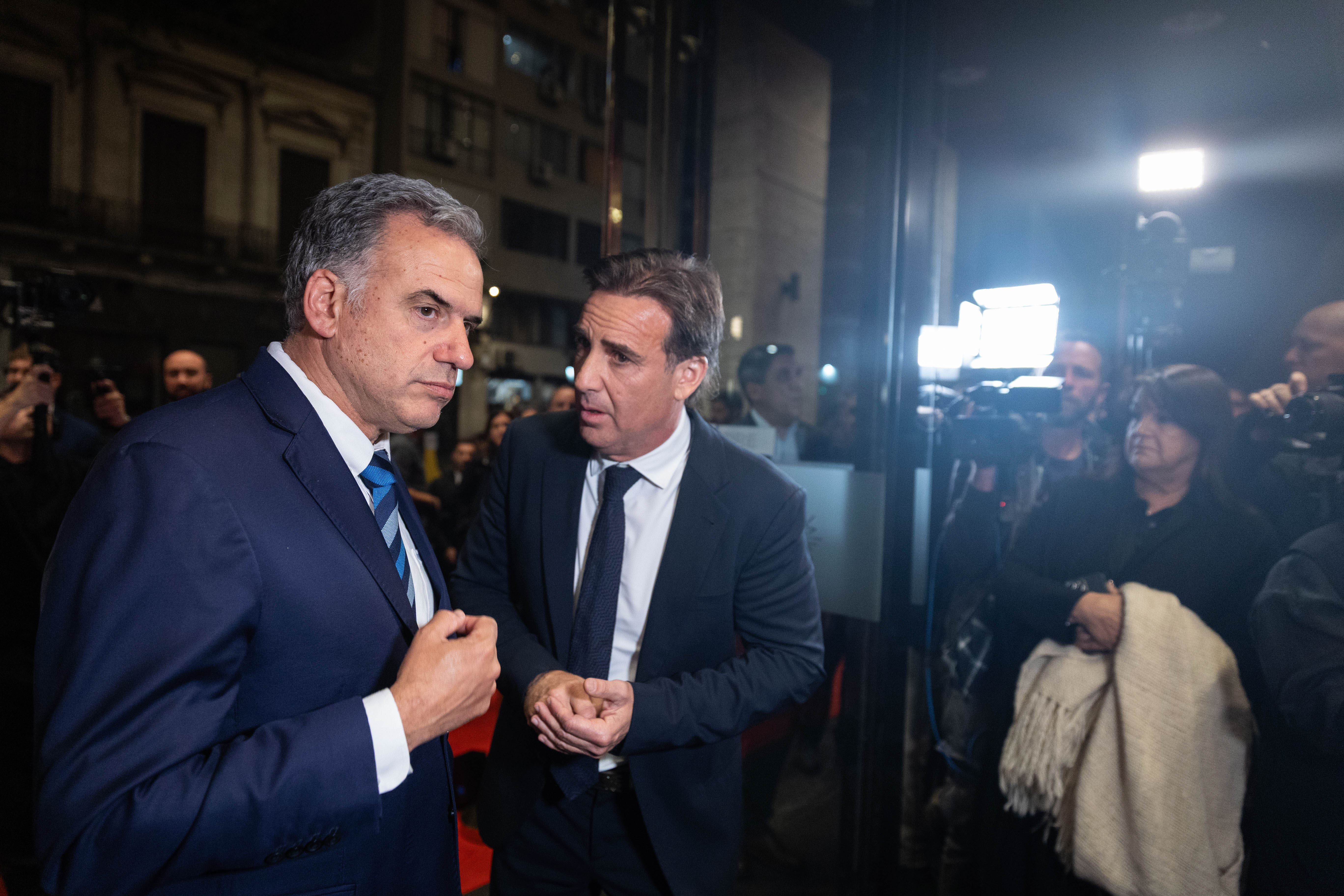 Orsi dialoga con directivo de Ayax en el ingreso al Auditorio Nacional del Sodre. Varias personas los observan. 