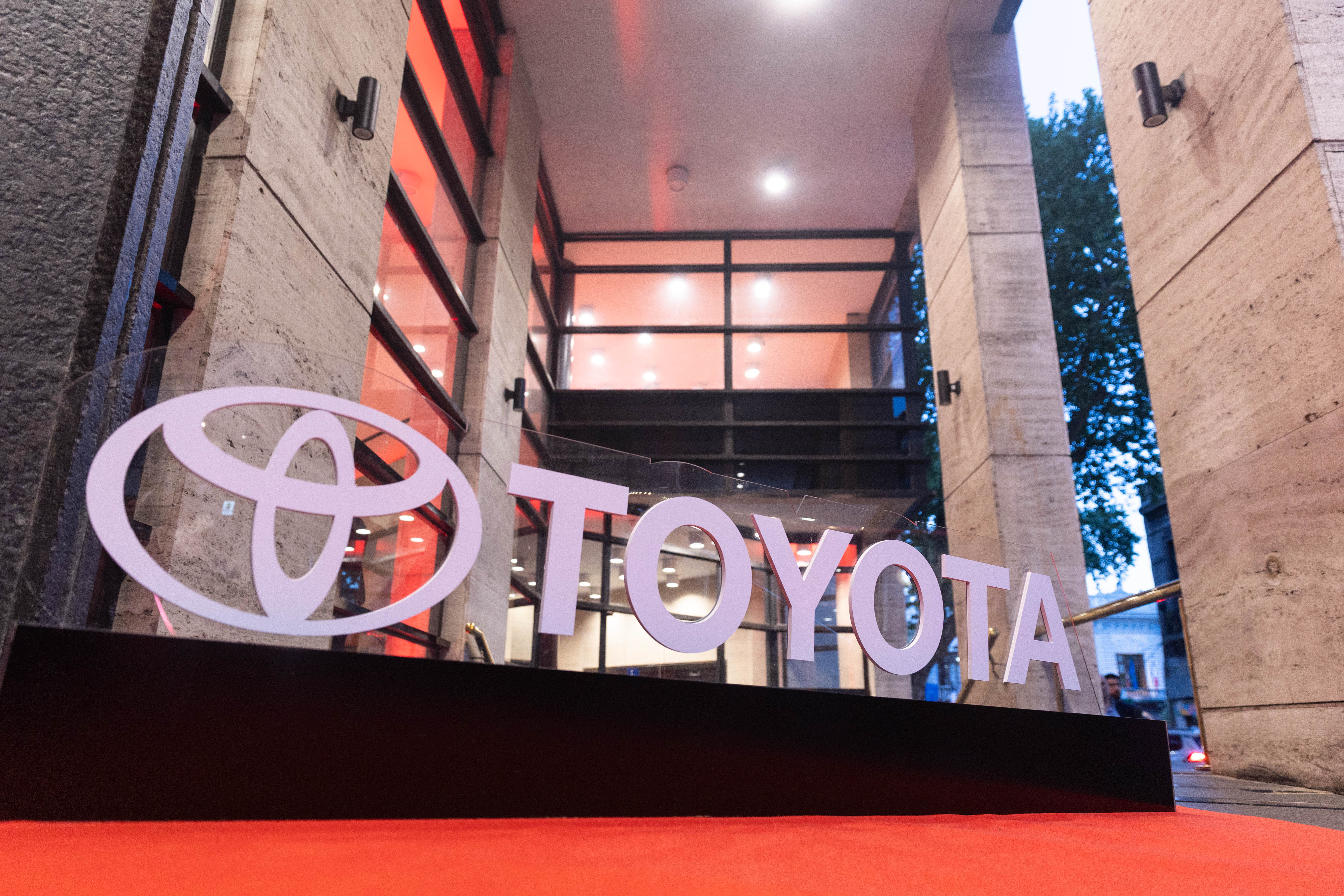 Primer plano del logotipo y nombre Toyota en un cartel, sobre una alfombra roja, en el ingreso al Auditorio Nacional del Sodre. 