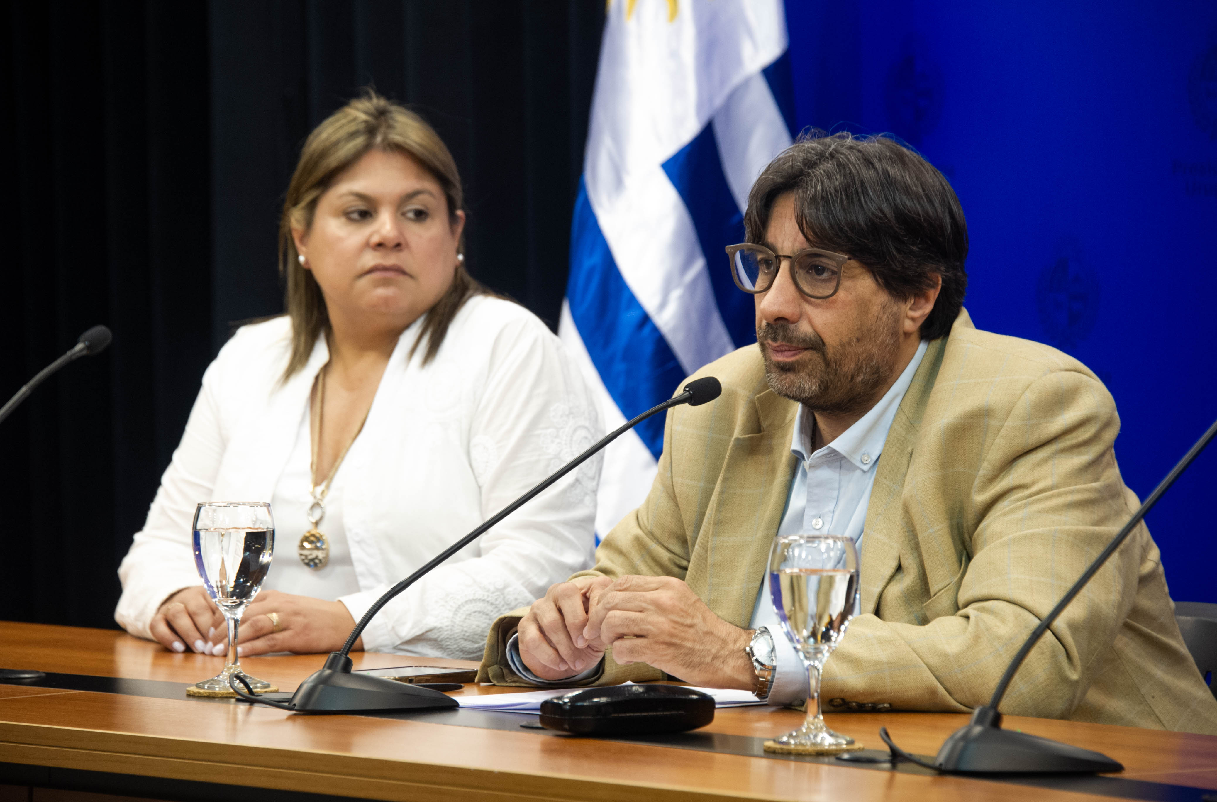 Presidente de la Unasev diserta sentado en mesa con micrófono junto a la directora del organismo.