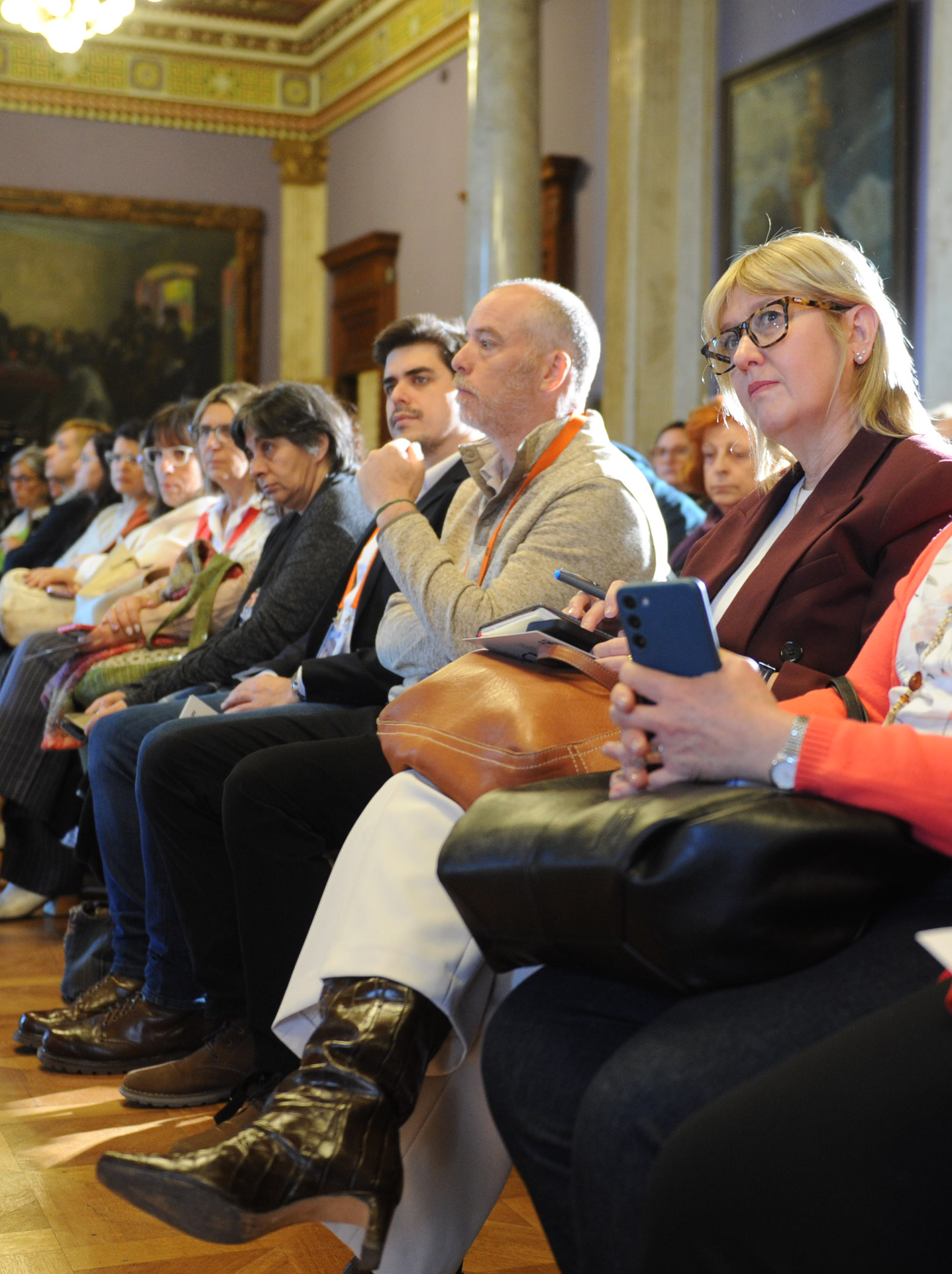 Ministra de Salud Pública junto a otras autoridades y público sentada en primera fila del salón de eventos especiales.
