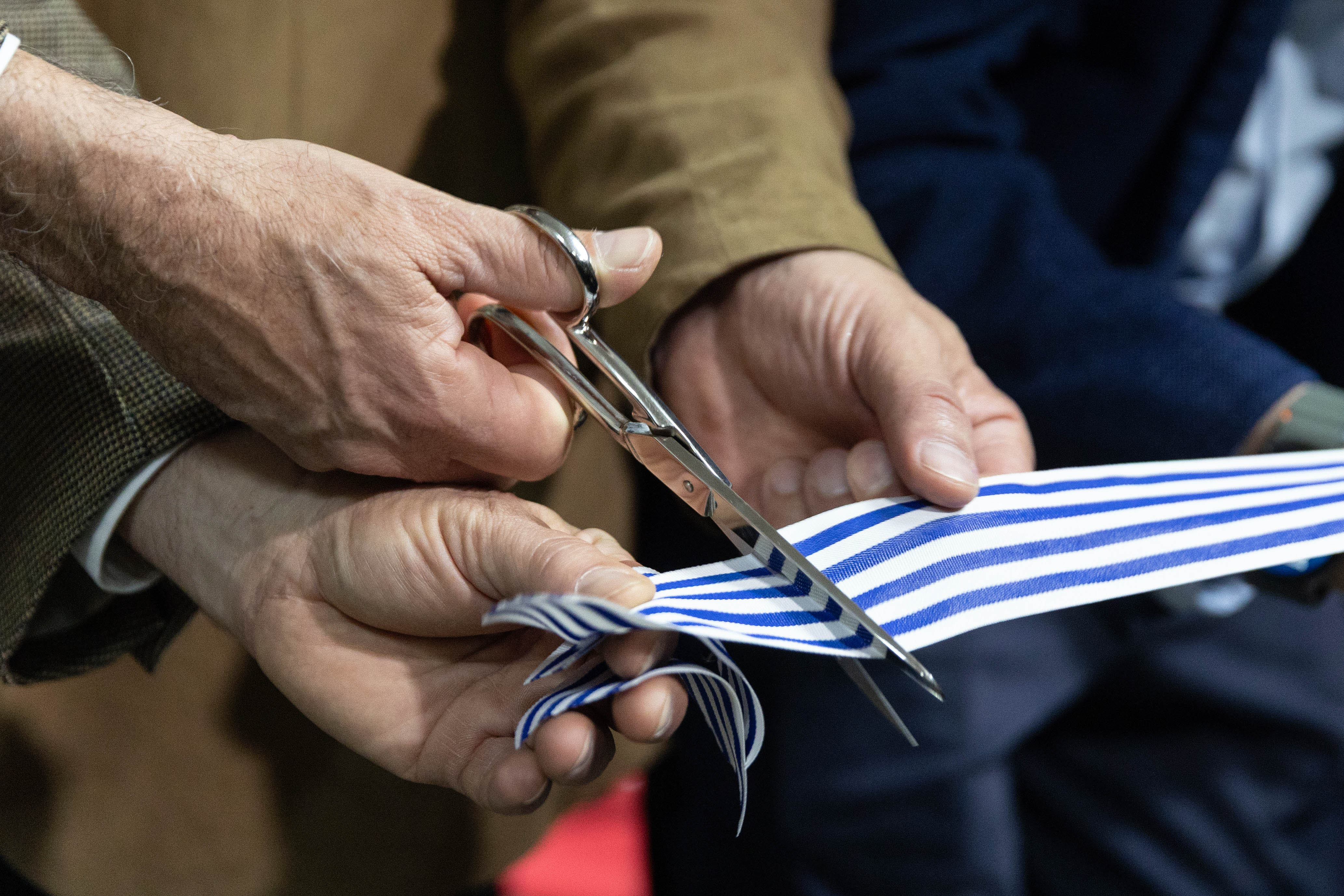Primer plano de unas tijeras cortando una cinta con franjas azules y blancas durante la ceremonia de inauguración.