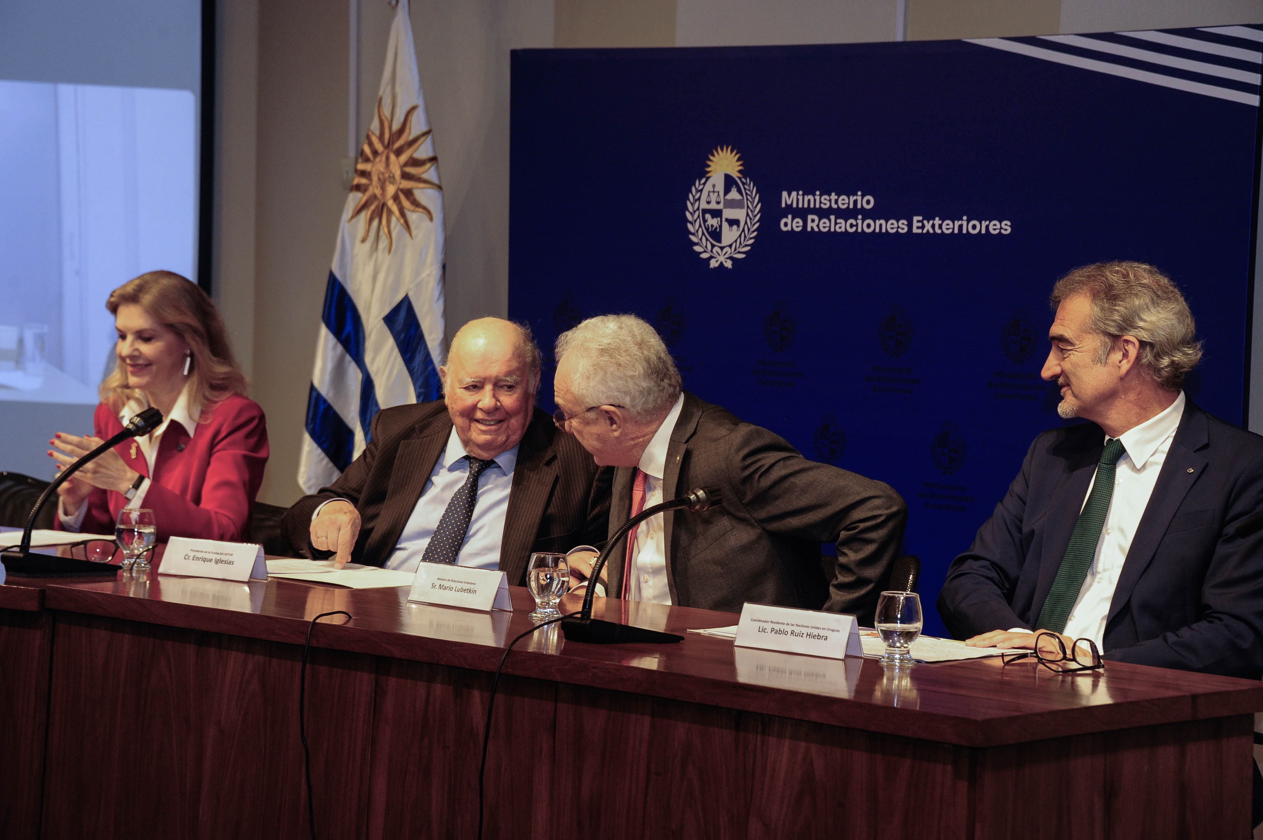 El canciller dialoga con el presidente de la Fundación Astur sentados en mesa con micrófonos. A sus costados hay otras autoridades.