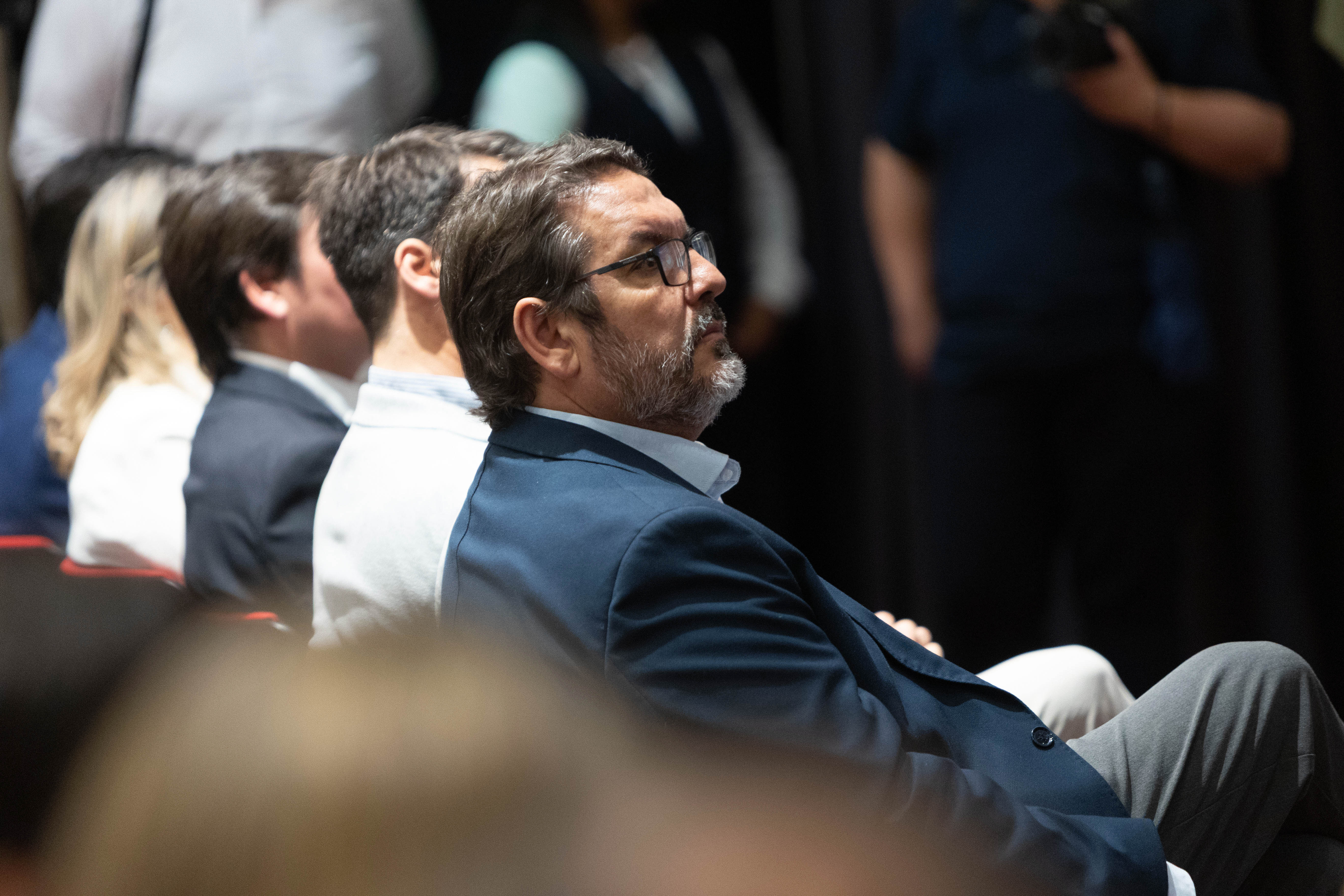 Plano lateral del público sentado en la platea mirando hacia el escenario.