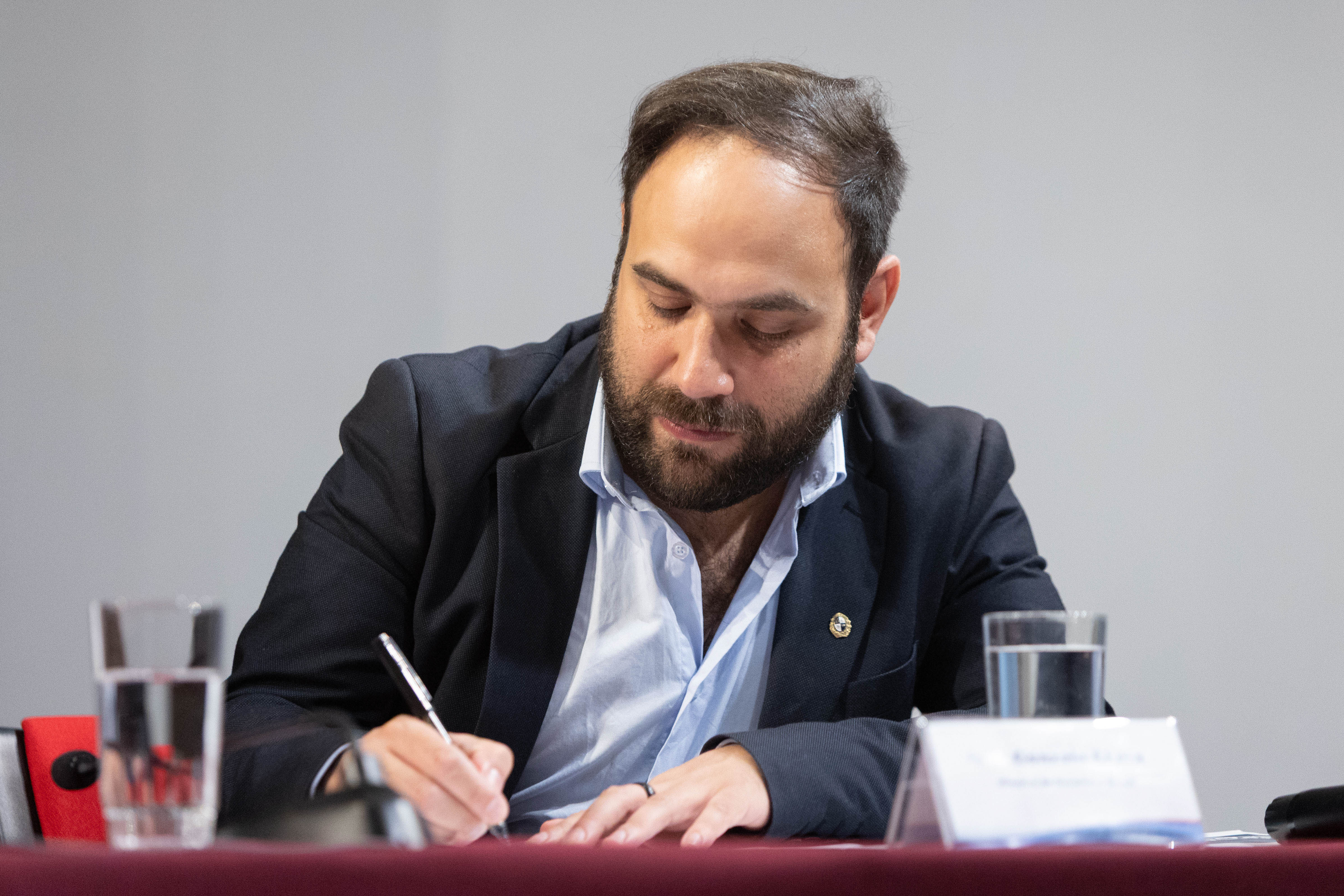 Primer plano del ministro de Desarrollo Social, sentado en mesa, firmando unos documentos.