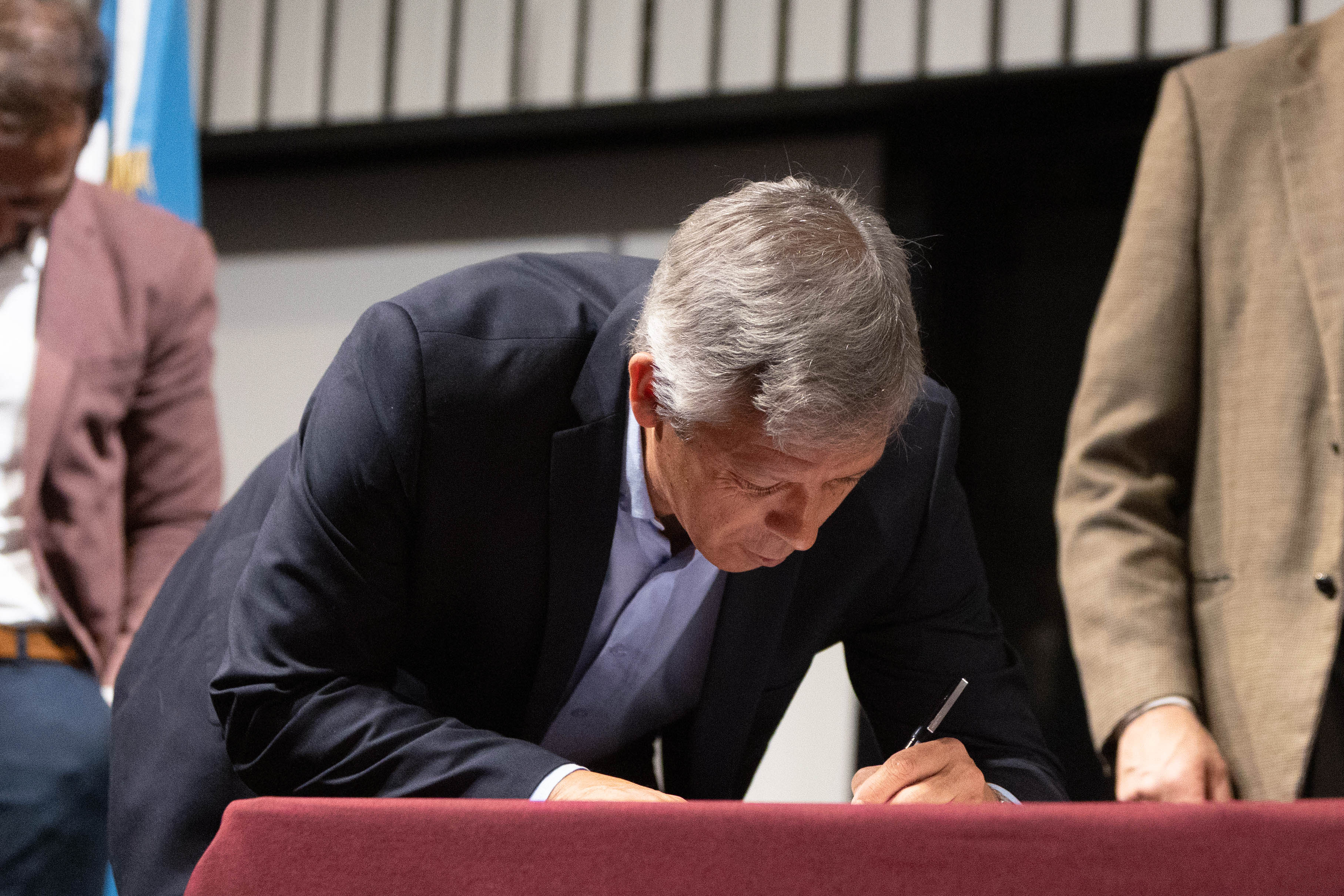 El secretario Nacional del Deporte firma unos documentos sobre una mesa.