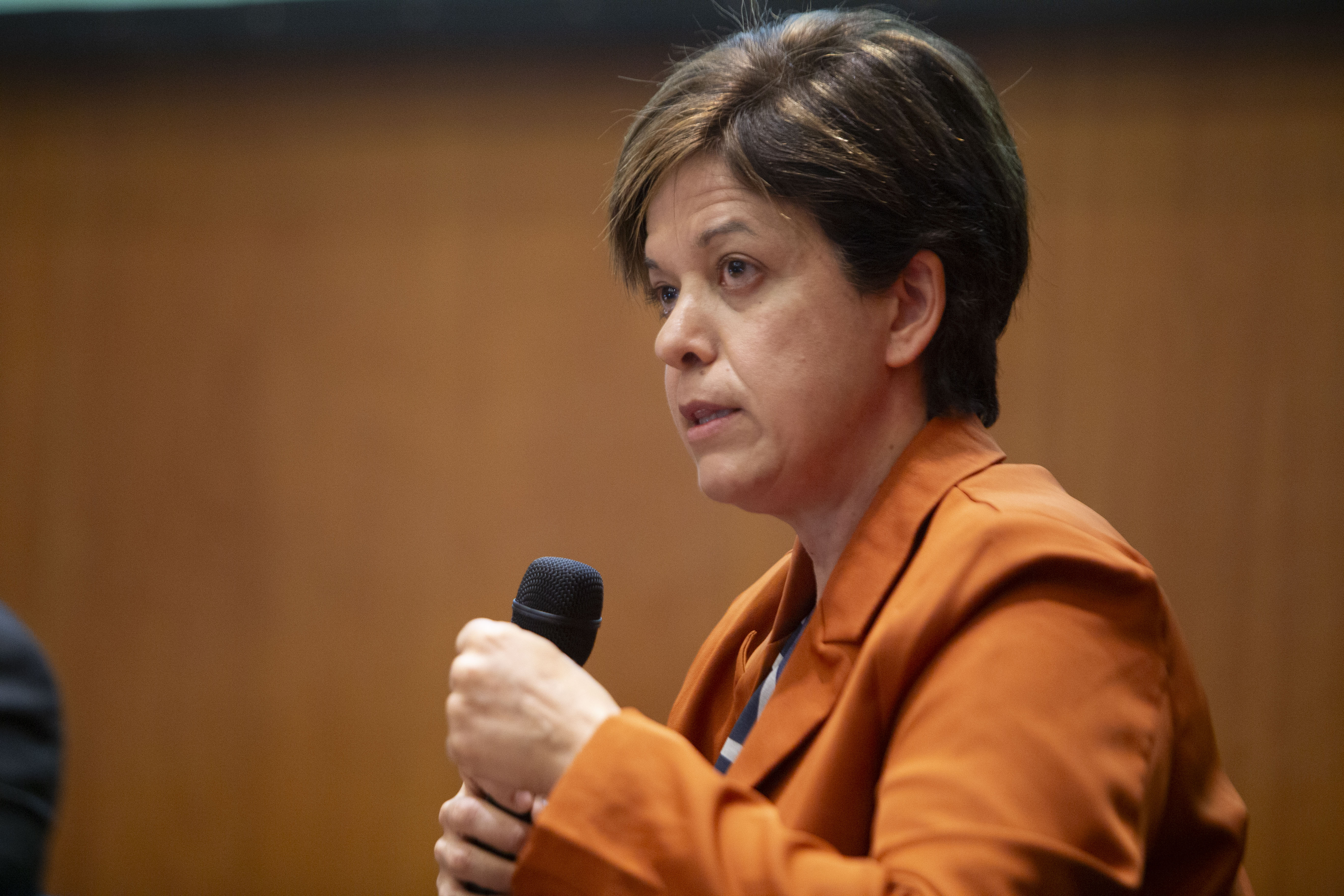 Directora general de la Salud diserta de pie, con micrófono en mano.