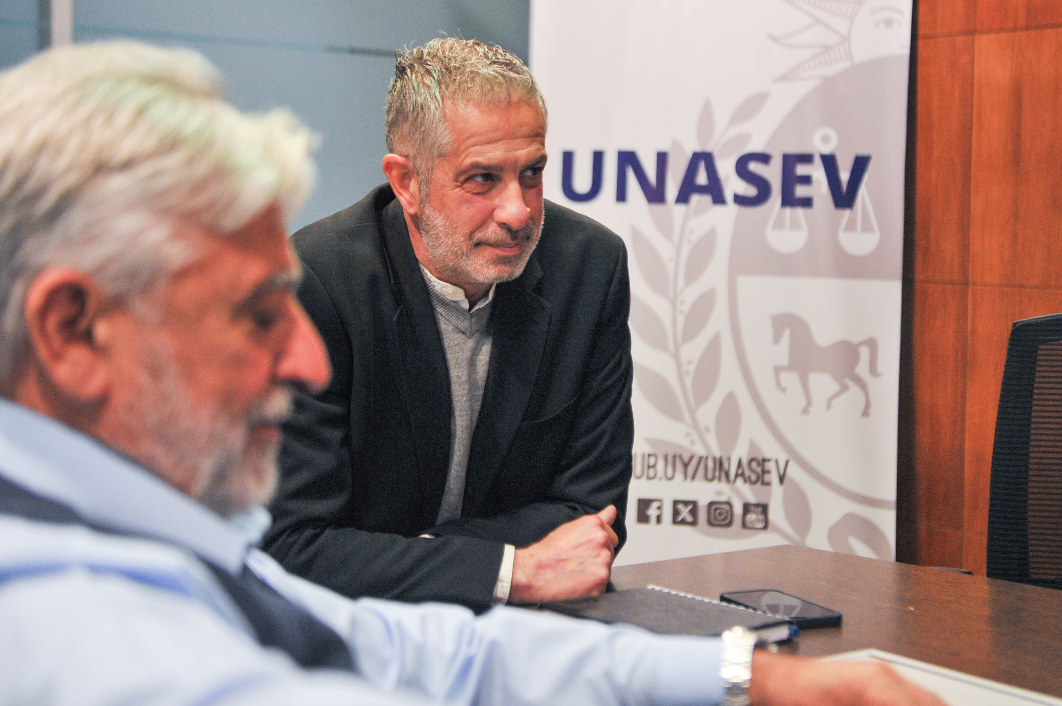 Otra perspectiva del presidente de Unasev y los representantes de las intendencias sentados en mesa dialogando entre sí.