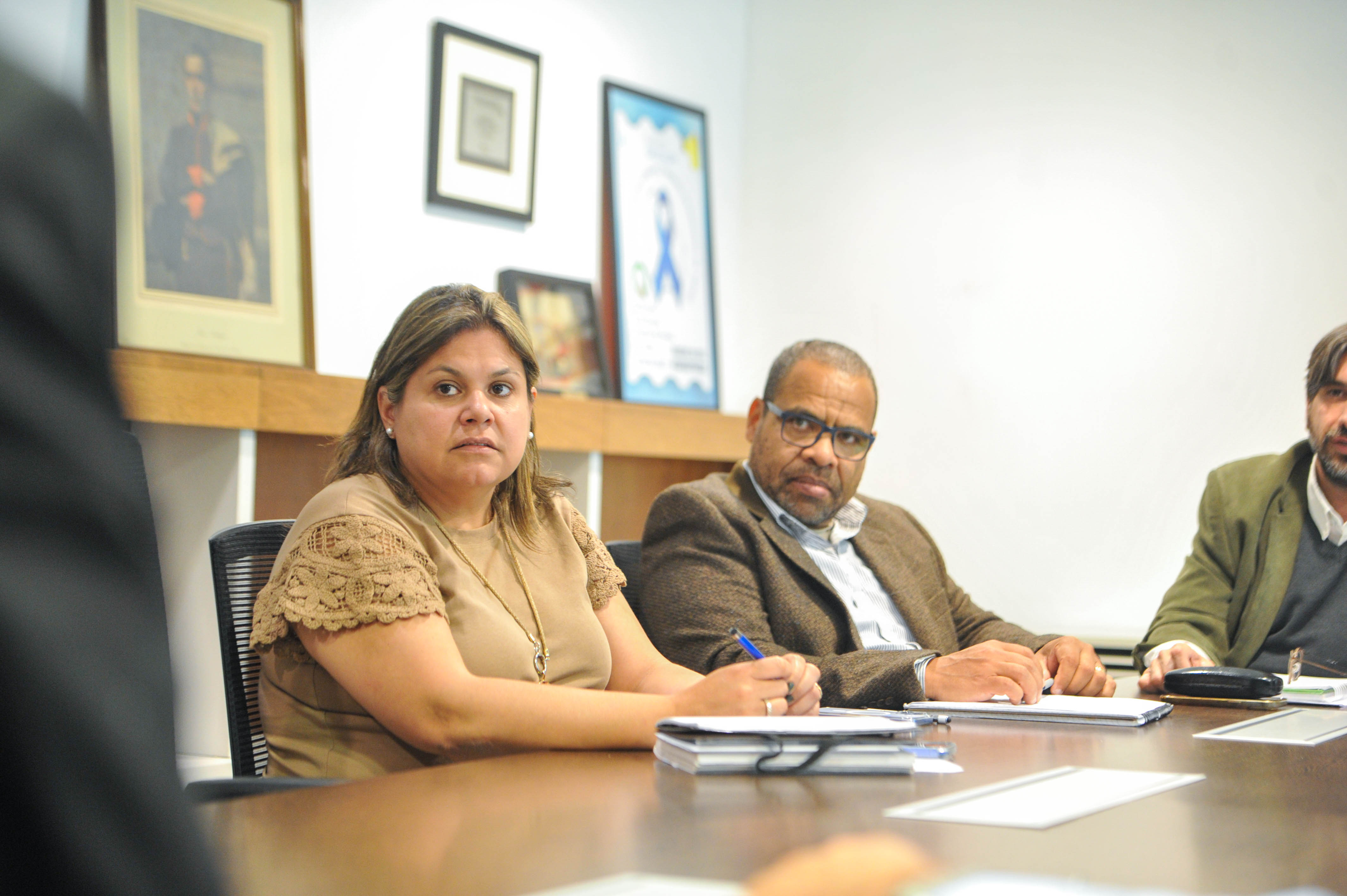 Dos directores de Unasev sentados en la mesa miran hacia un lado escuchando a una persona.