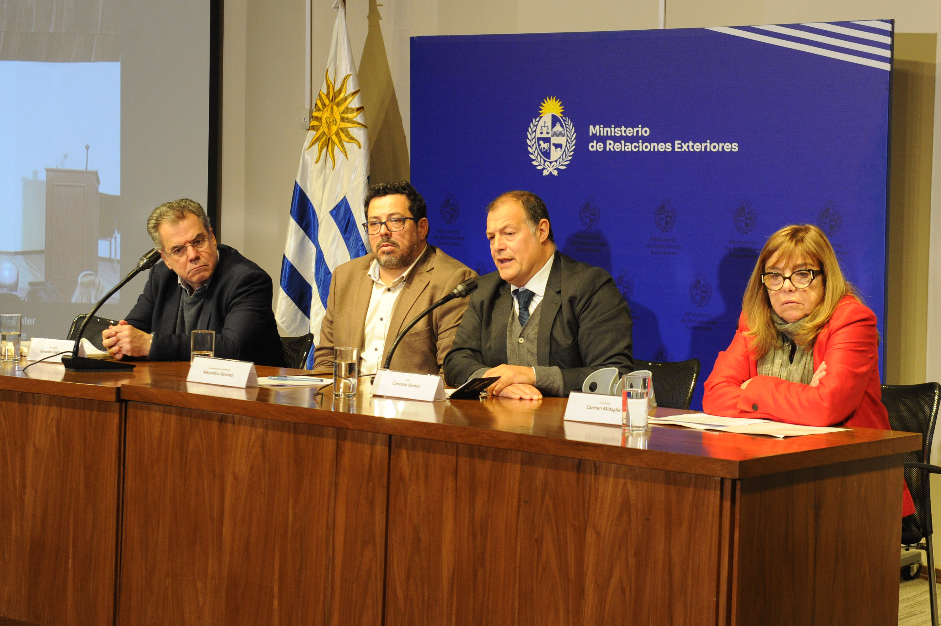 El secretario general del CLAD diserta mientras el secretario de Presidencia y otros dos oradores lo observan.