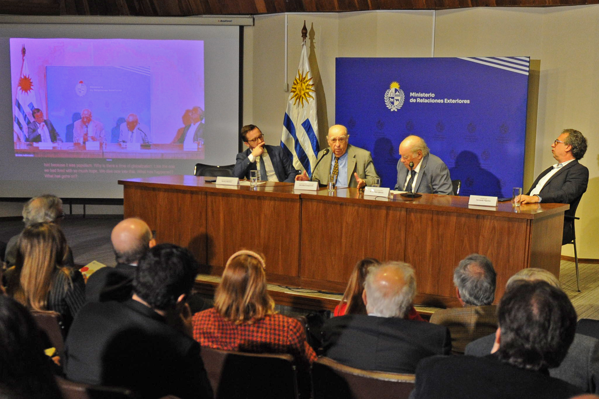 Expresidente Julio María Sanguinetti diserta en mesa con micrófono junto a otras tres autoridades que lo observan.