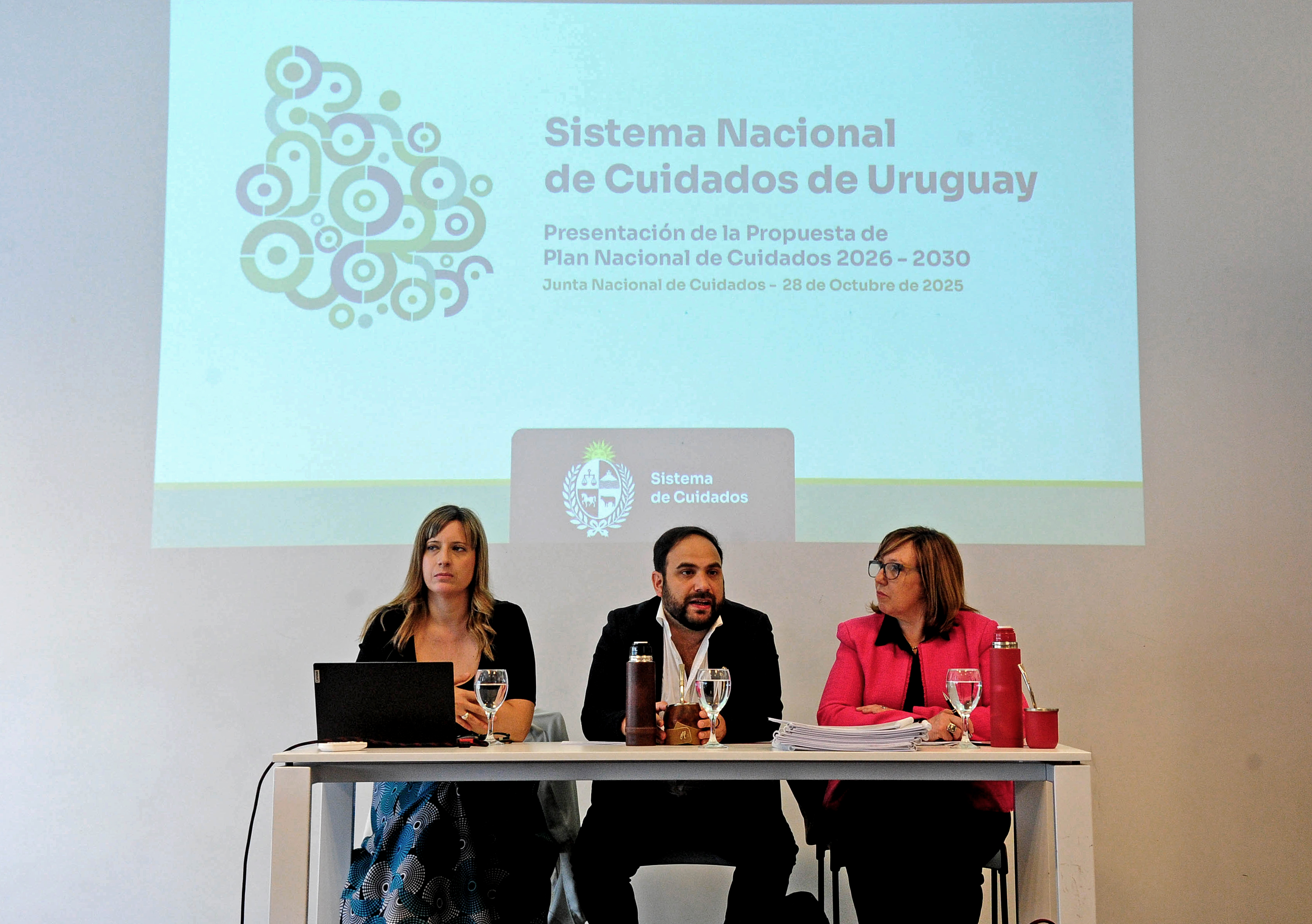 Ministro de Desarrollo sentado diserta sentado en mesa junto a la secretaria Nacional y a la directora de Cuidados.