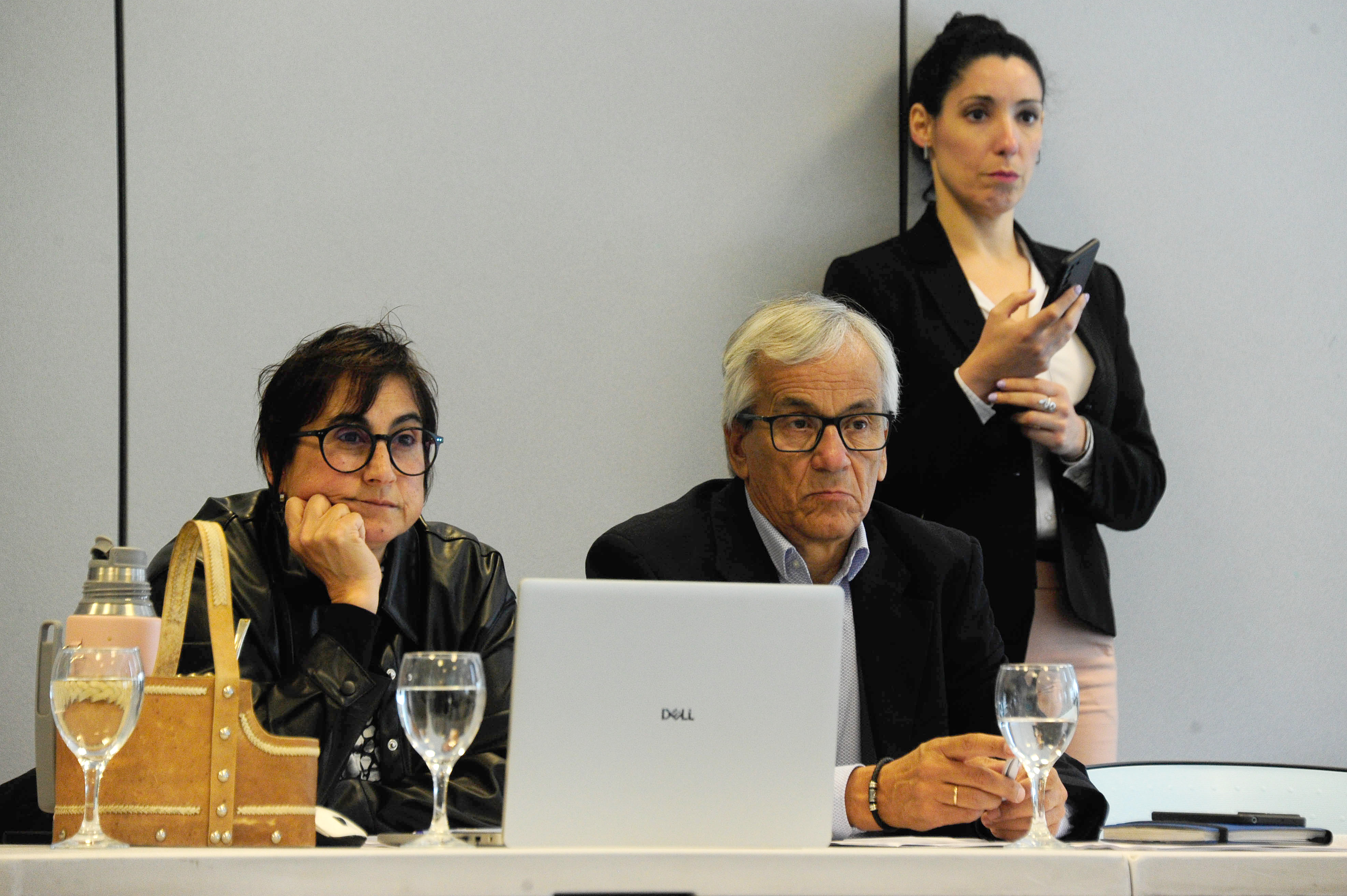 Ministro de Trabajo y presidenta de BPS sentados mirando hacia adelante. Atrás una mujer mira su celular.