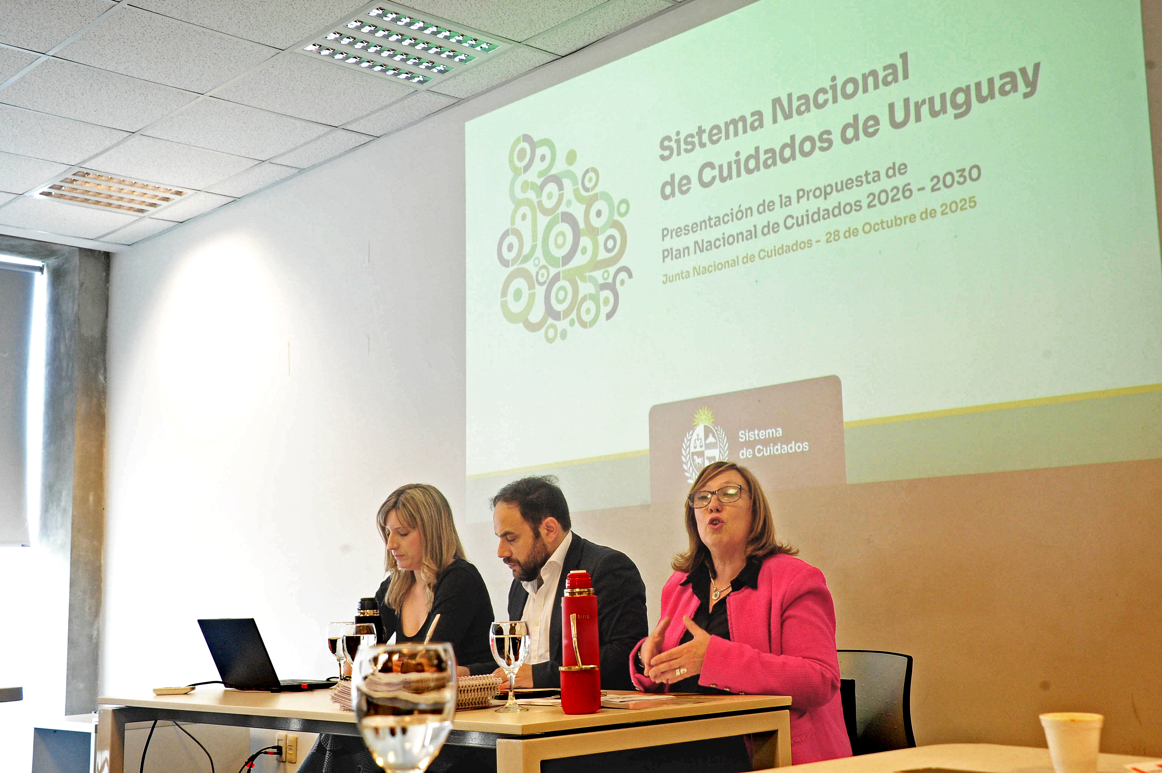 Secretaria nacional de Cuidados diserta junto al ministro de Desarrollo Social y la directora de Cuidados sentada en mesa.