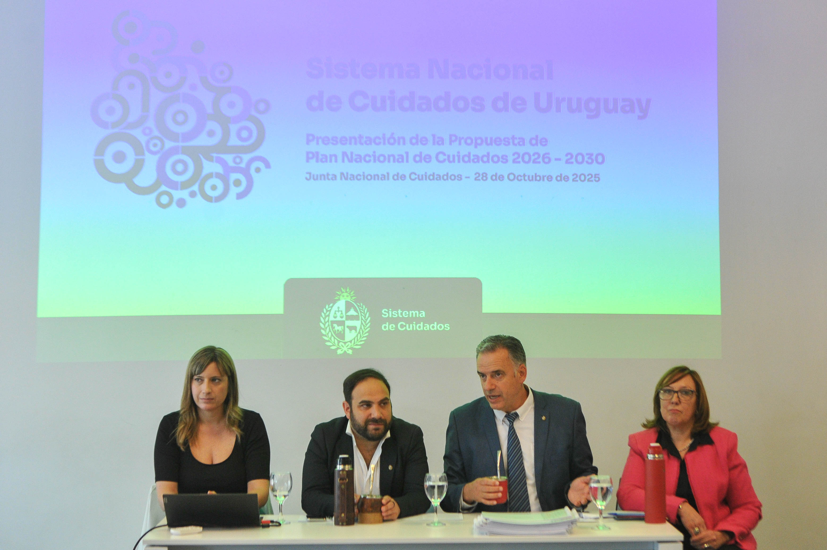 Orsi diserta sentado en mesa junto al ministro de Desarrollo Social y autoridades de la cartera.