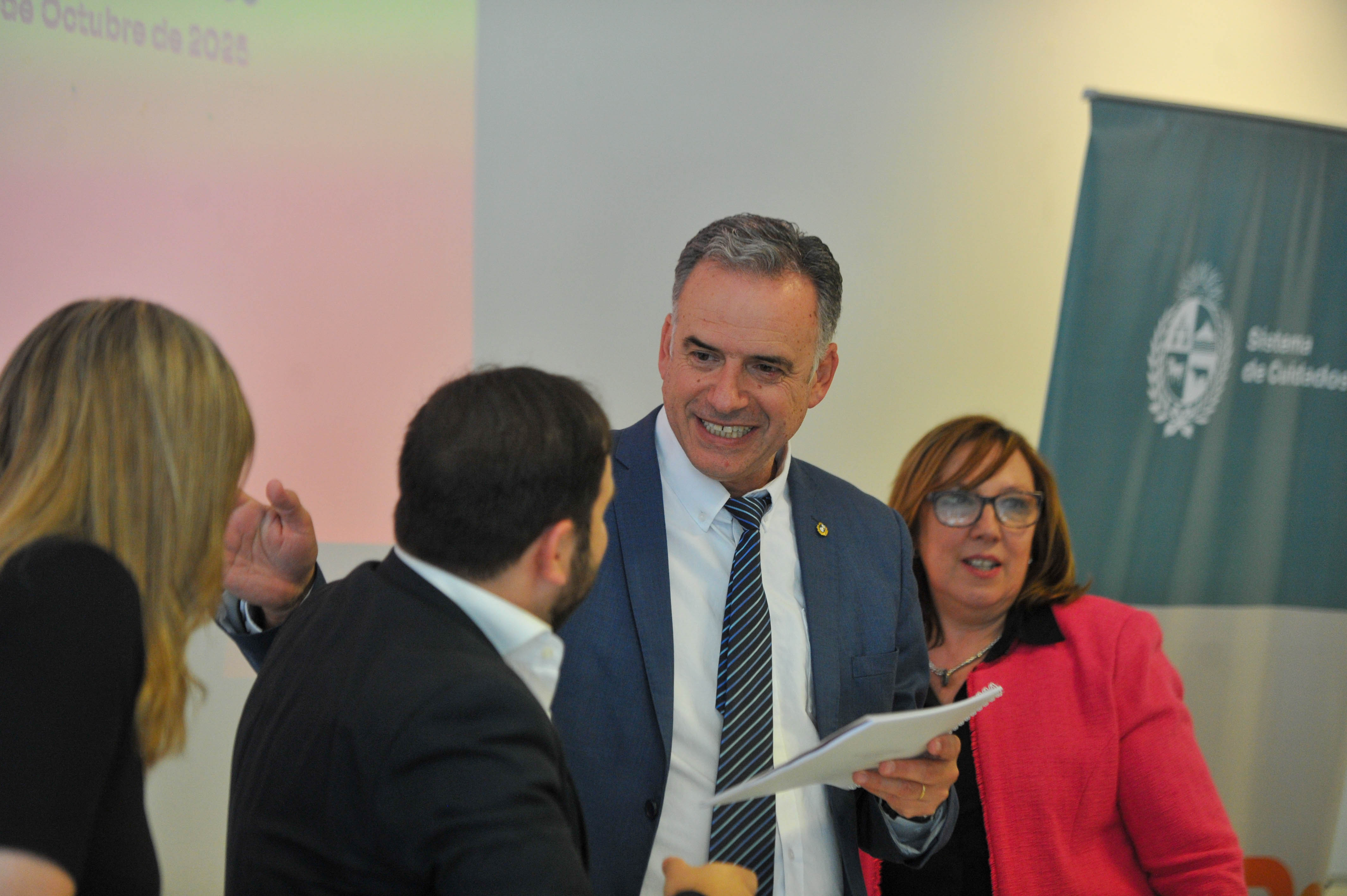 Orsi sonriente dialoga con el ministro de Desarrollo Social mientras la secretaria y la directora de Cuidados los observan.