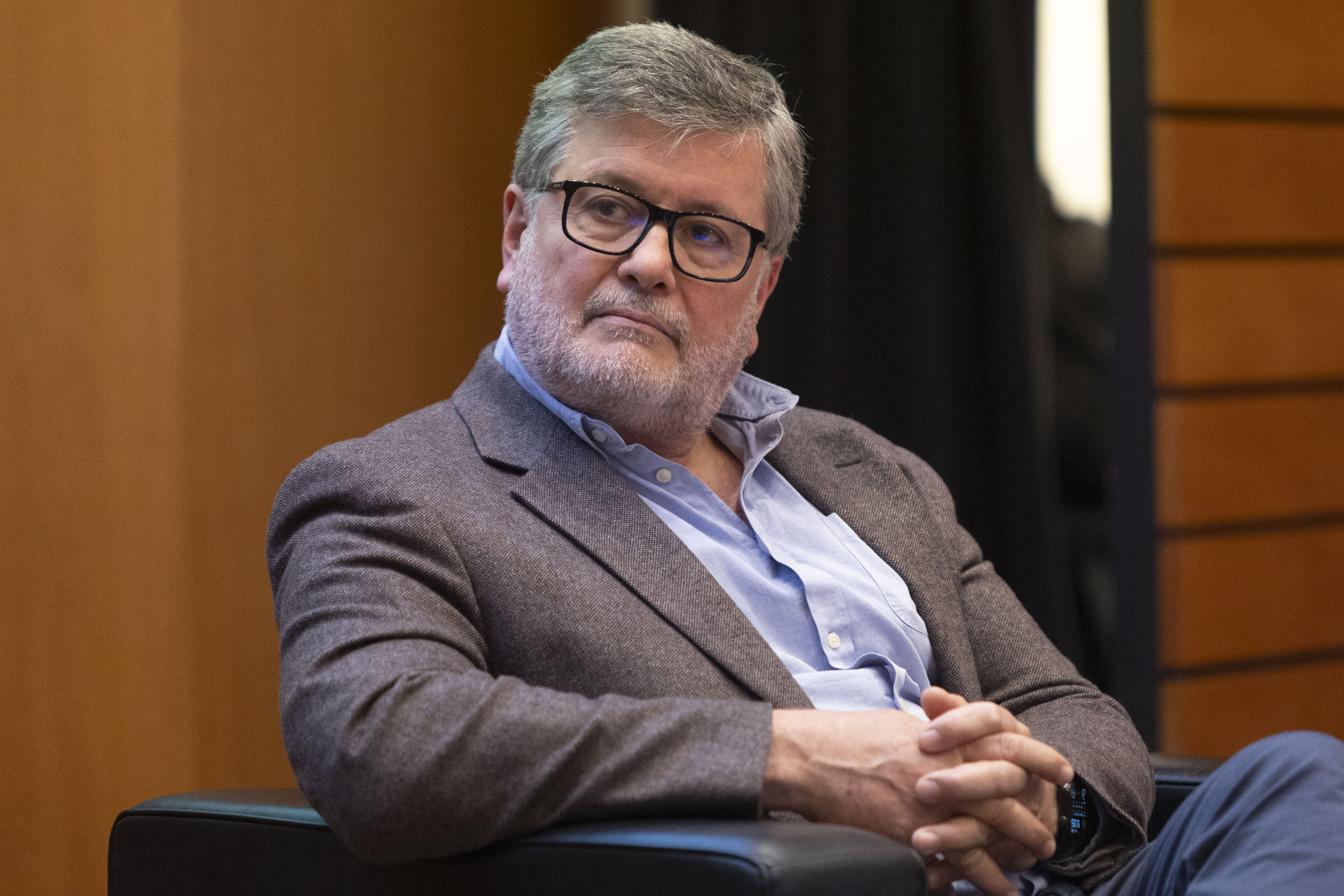 Director de la Oficina de Servicio Civil sentado en un sillón en el escenario escucha atentamente una disertación.