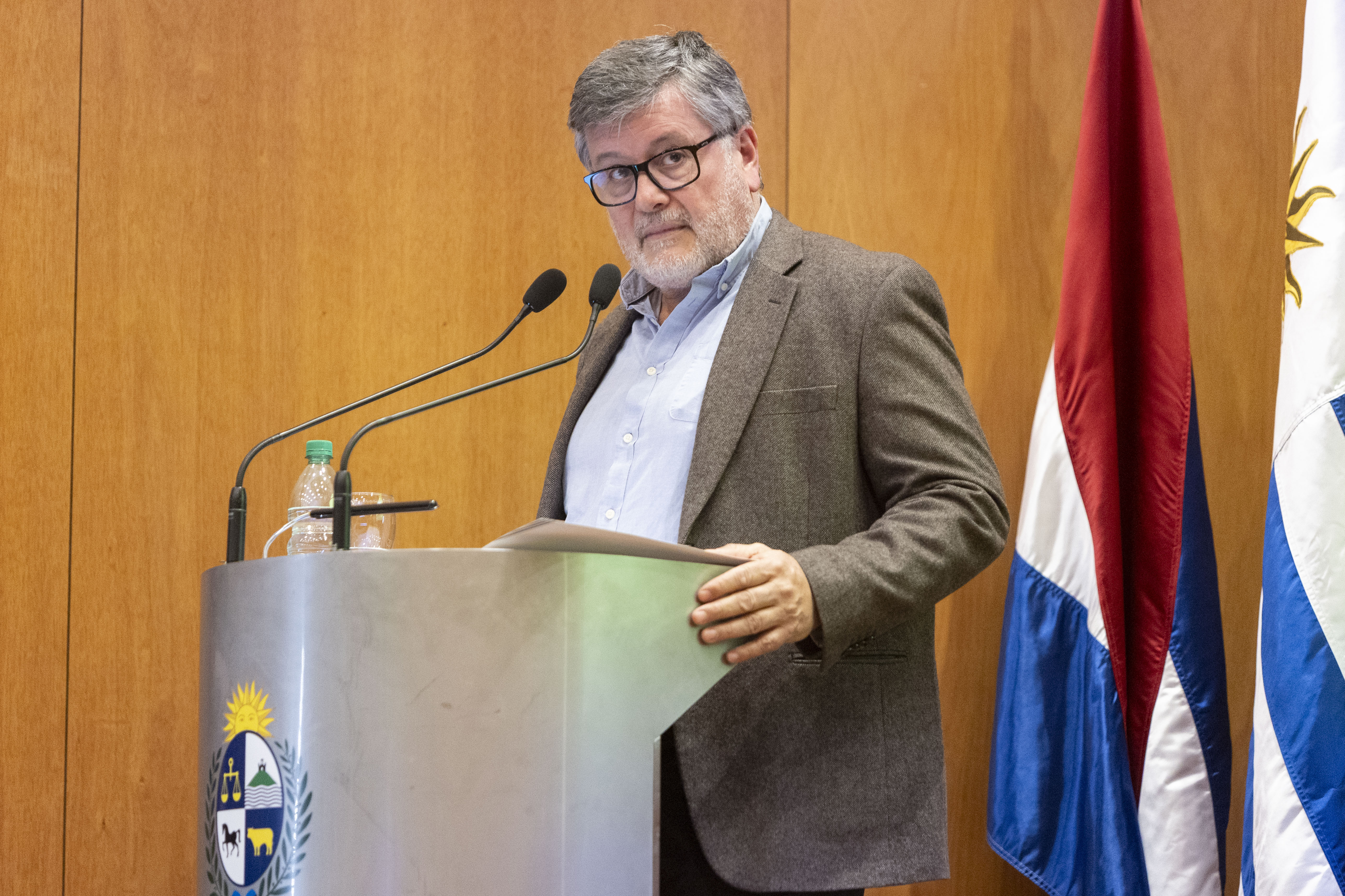 Director de la Oficina de Servicio Civil diserta de pie en atril con micrófono en el escenario.