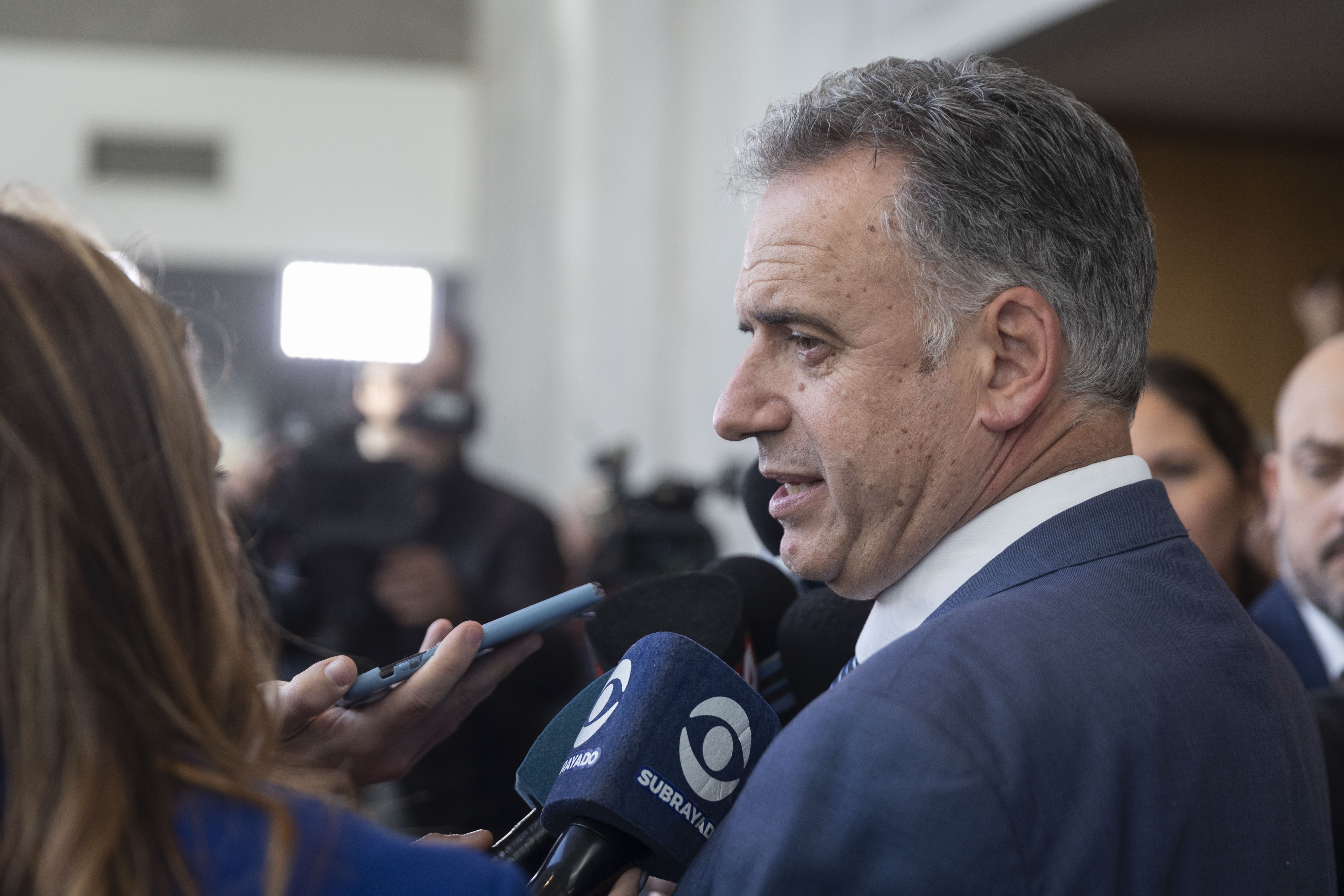 Orsi, de perfil, dialoga con periodistas frente a varios micrófonos de medios de comunicación.