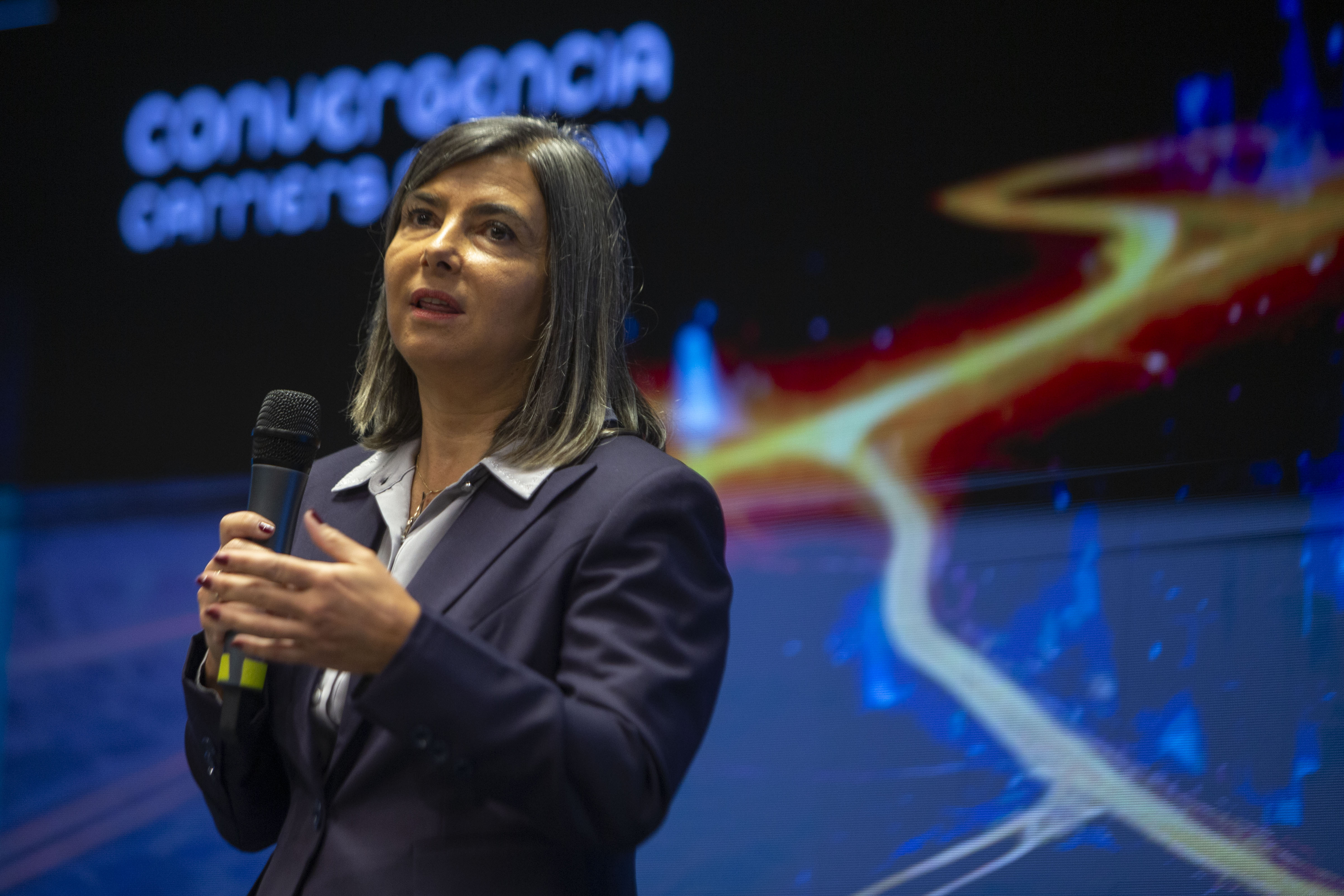 Primer plano de la gerenta general de Antel, de pie en el escenario disertando con micrófono en mano.
