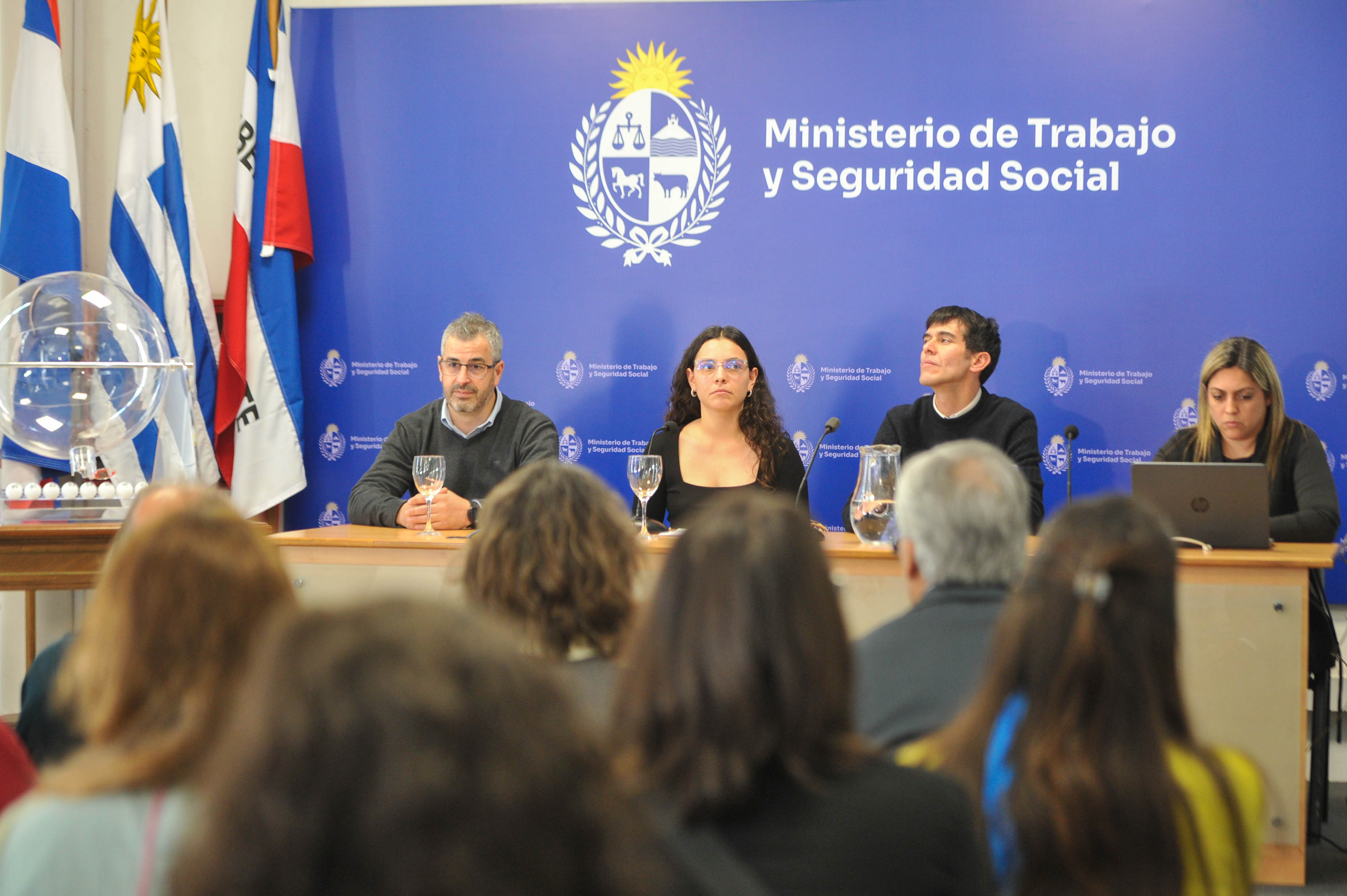 Autoridades sentadas en la mesa principal mientras el público los observa. Atrás se observa cartel azul con logo del ministerio.