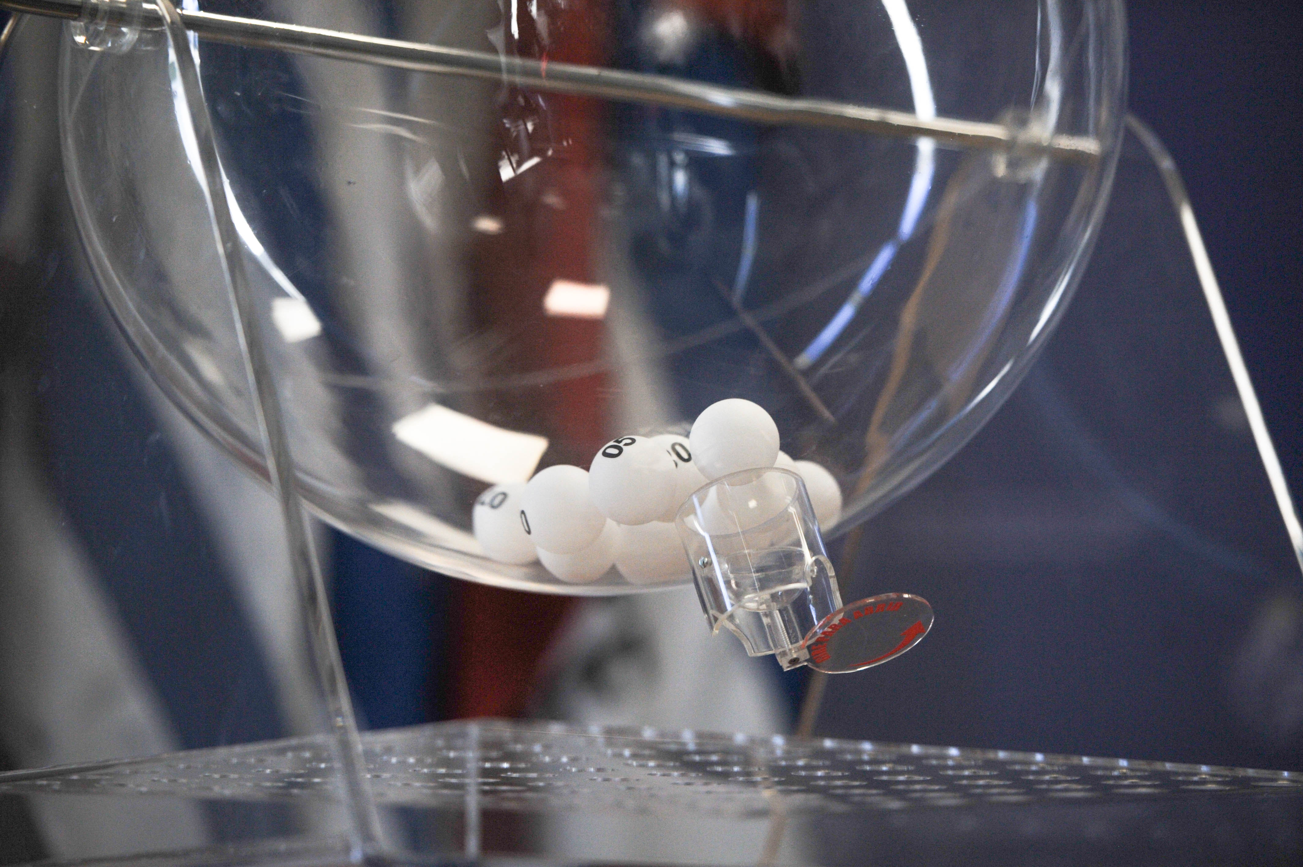 Primer plano del bolillero transparente con bolas blancas numeradas en su interior.