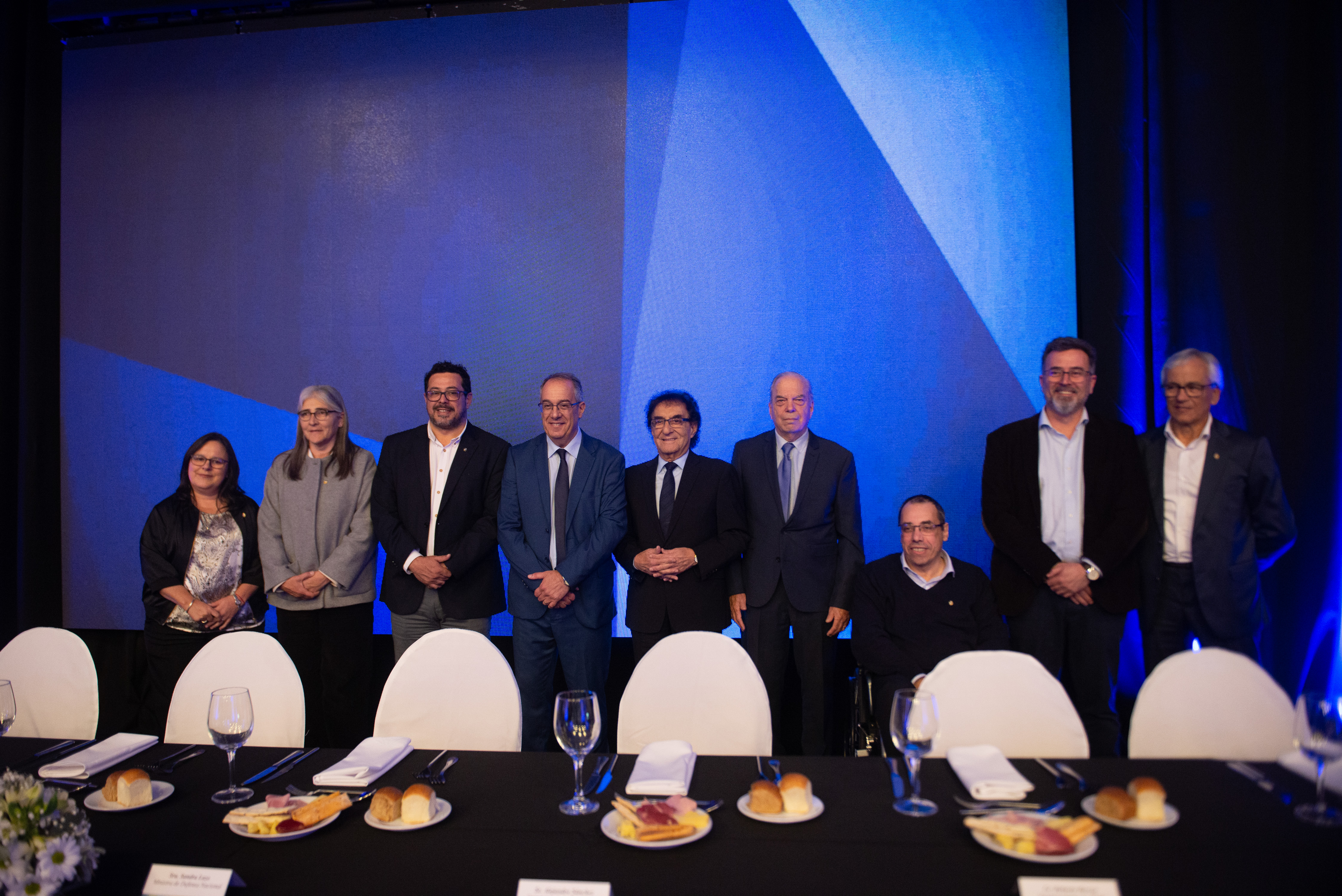 Secretario de Presidencia, varios ministros de Estado y autoridades de ADM posan sonrientes frente a cámara detrás de la mesa principal.