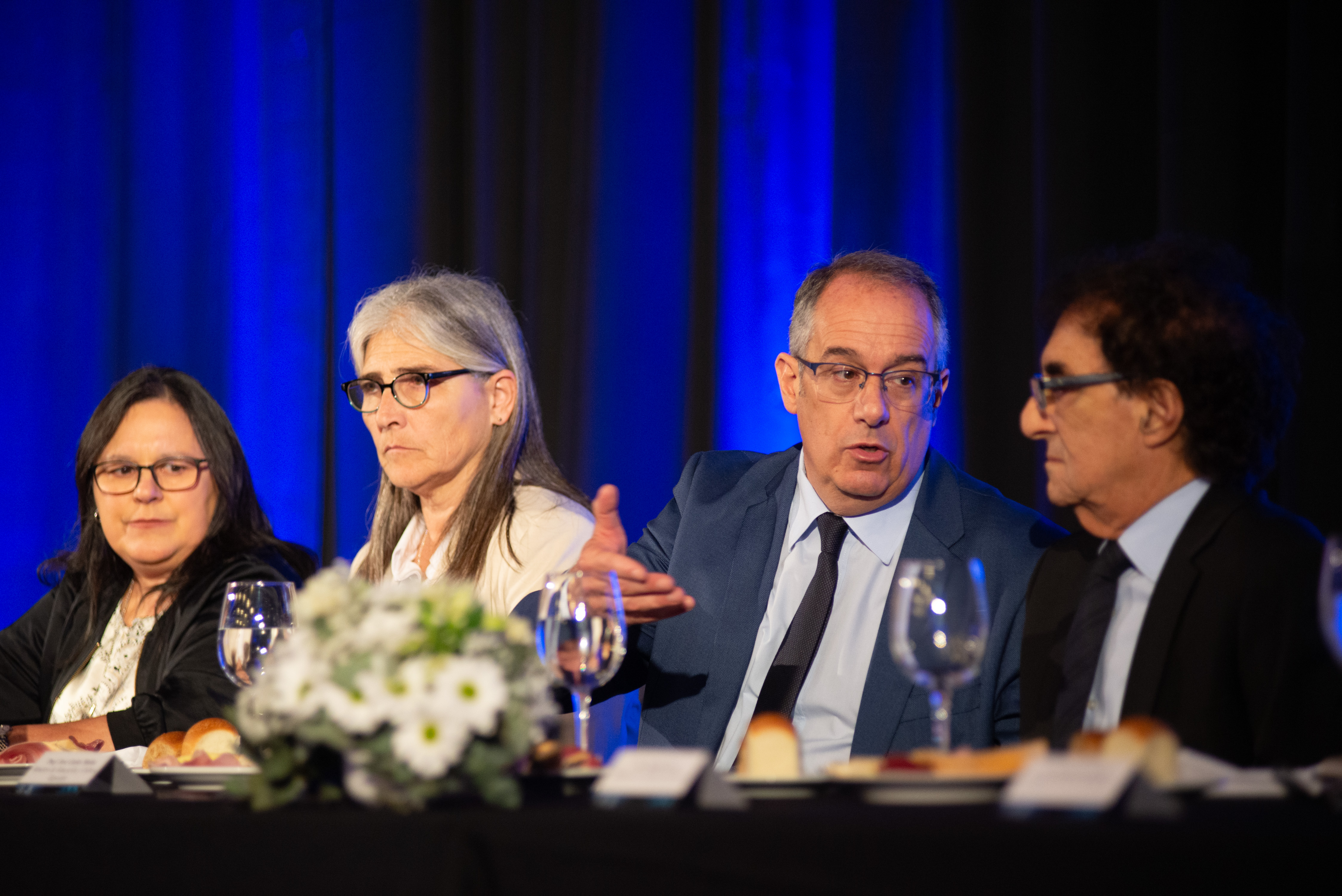 Ministro de Educación dialoga con el presidente de ADM sentado en mesa principal. A su costado hay otras autoridades de gobierno.