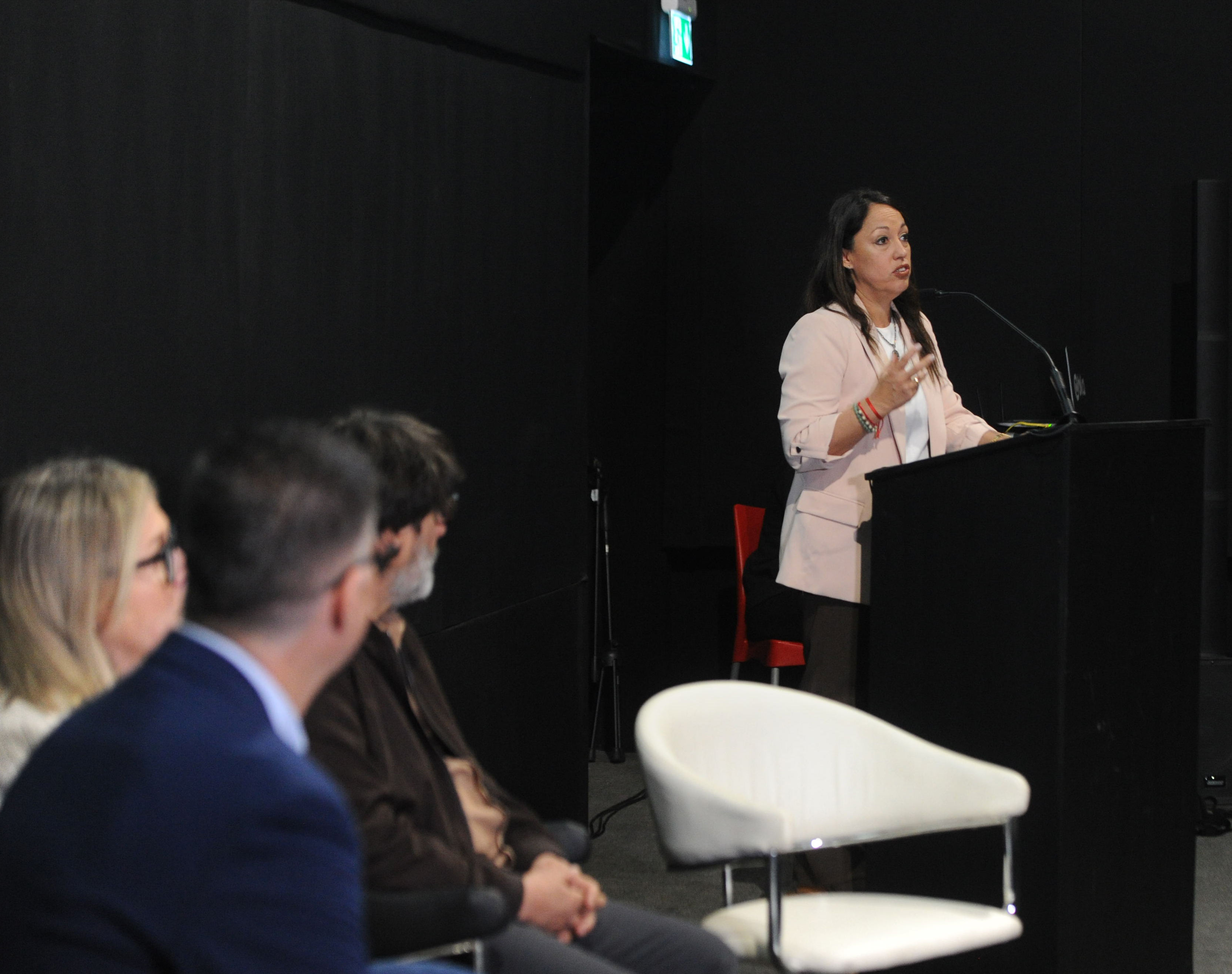 Ministra de Industria, de pie, diserta en atril con micrófono mientras las otras autoridades la observan.