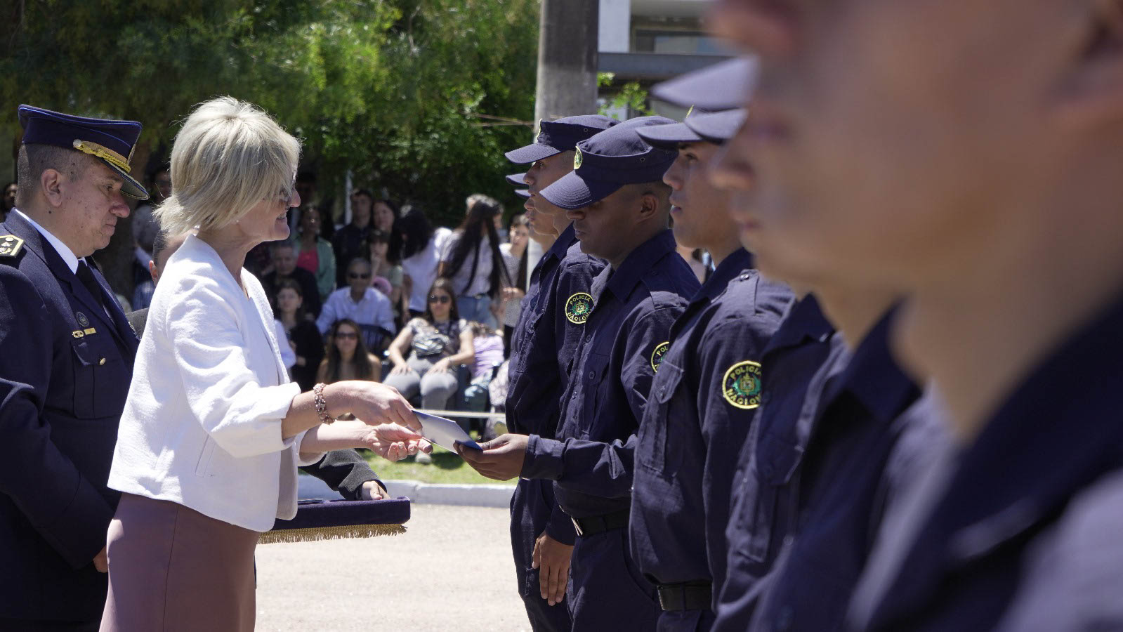 La subsecretaria del Interior entrega una placa a un policía durante la ceremonia de egreso, junto a otros agentes formados.