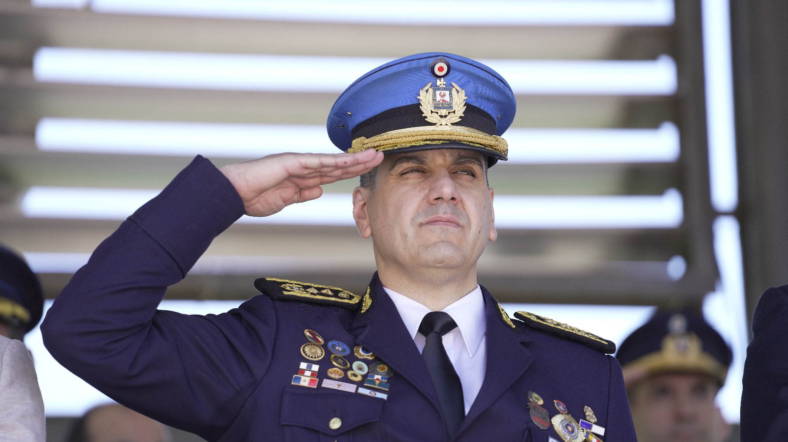 Primer plano del director nacional de la Educación Policial uniformado haciendo el saludo militar en el palco oficial.