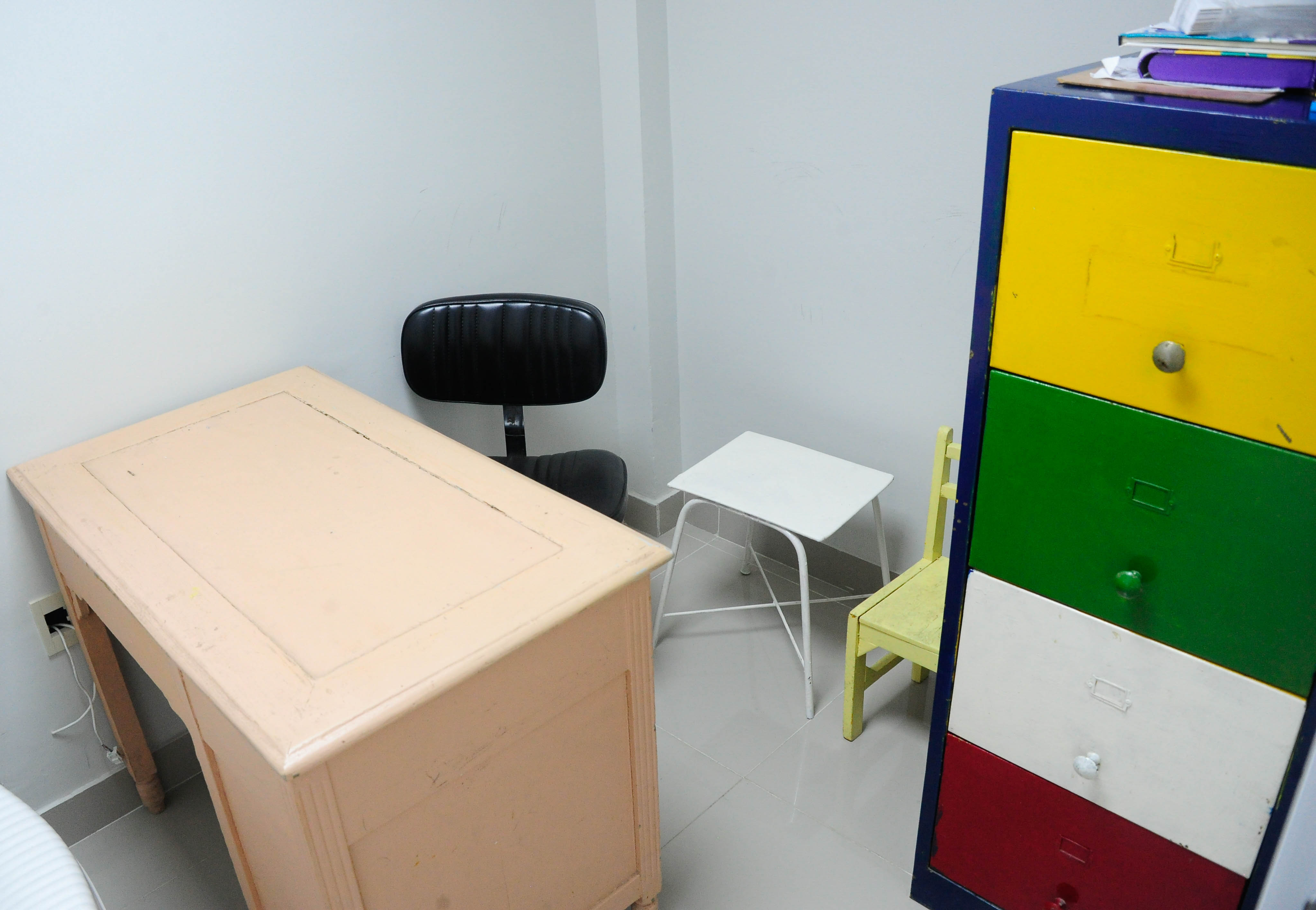 Plano general de consultorio pediátrico con un escritorio, una cajonera de colores y una pequeña mesa y silla.