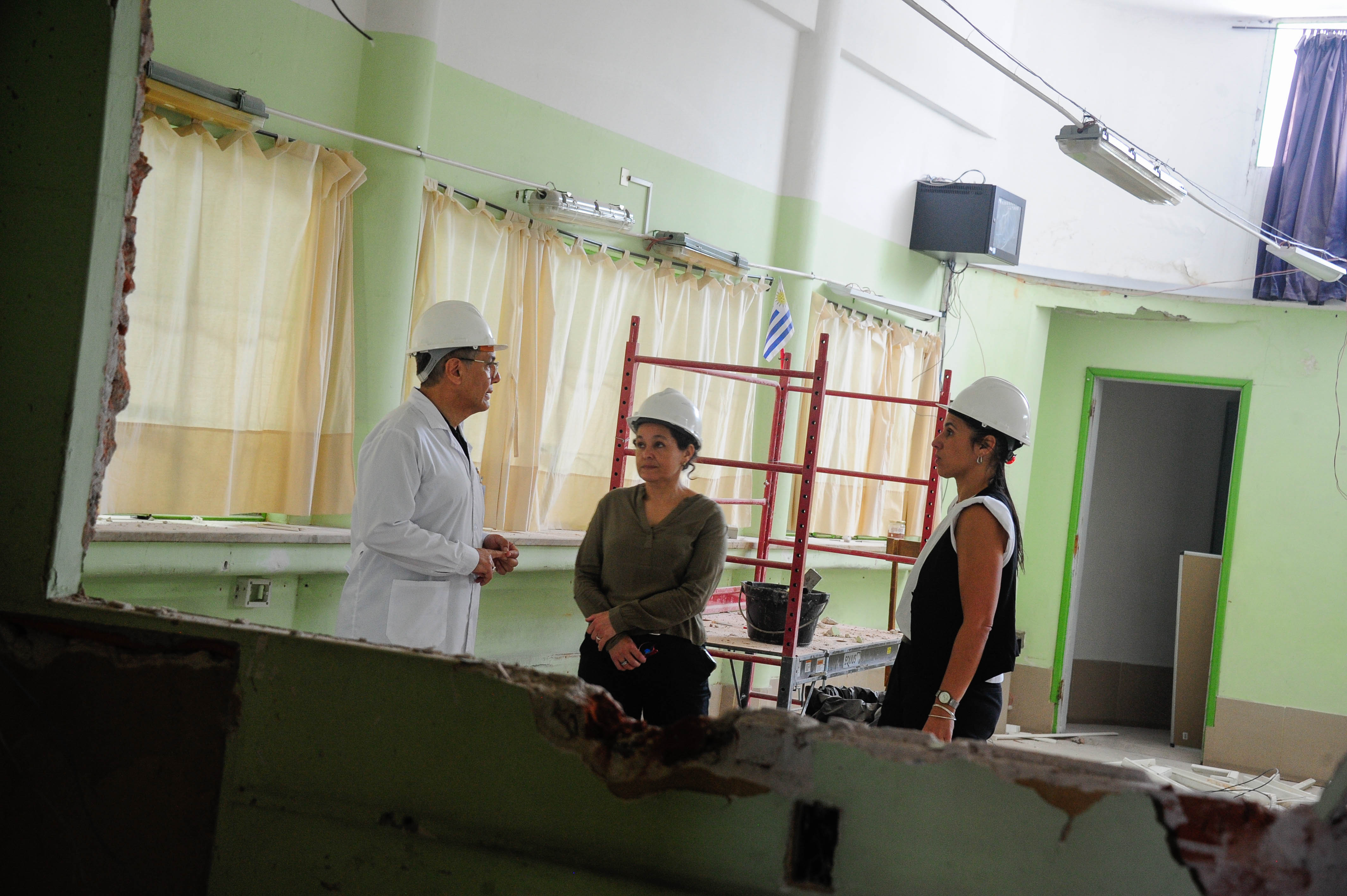 Plano general de una sala en reforma donde está el director general del Centro conversando con dos arquitectas.