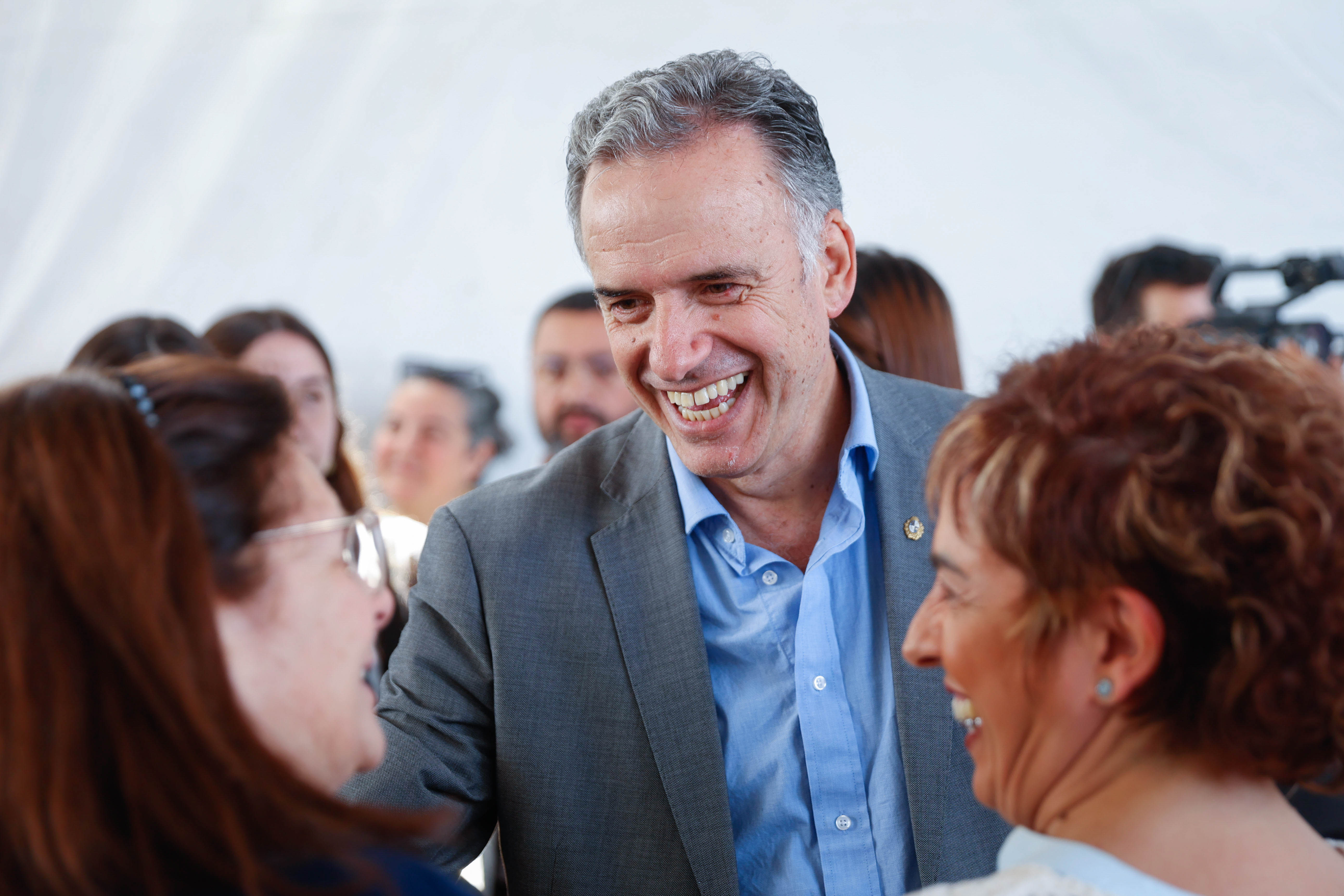 Orsi de pie dialoga sonriente con dos mujeres en la sala de ingreso del edificio de UTEC.