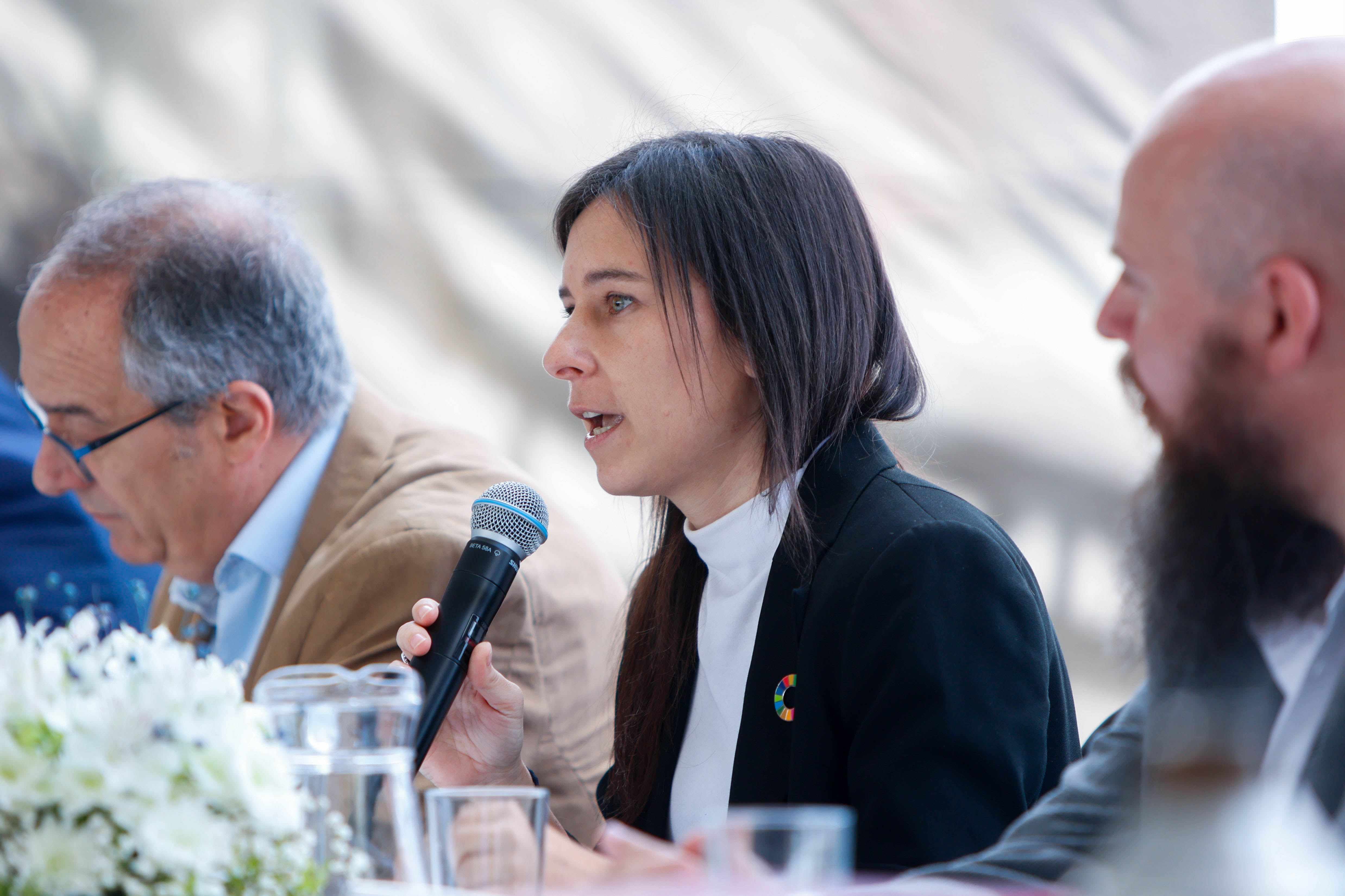 Rectora de la UTEC diserta sentada en mesa con micrófono en mano. A su costado está el ministro de Educación.