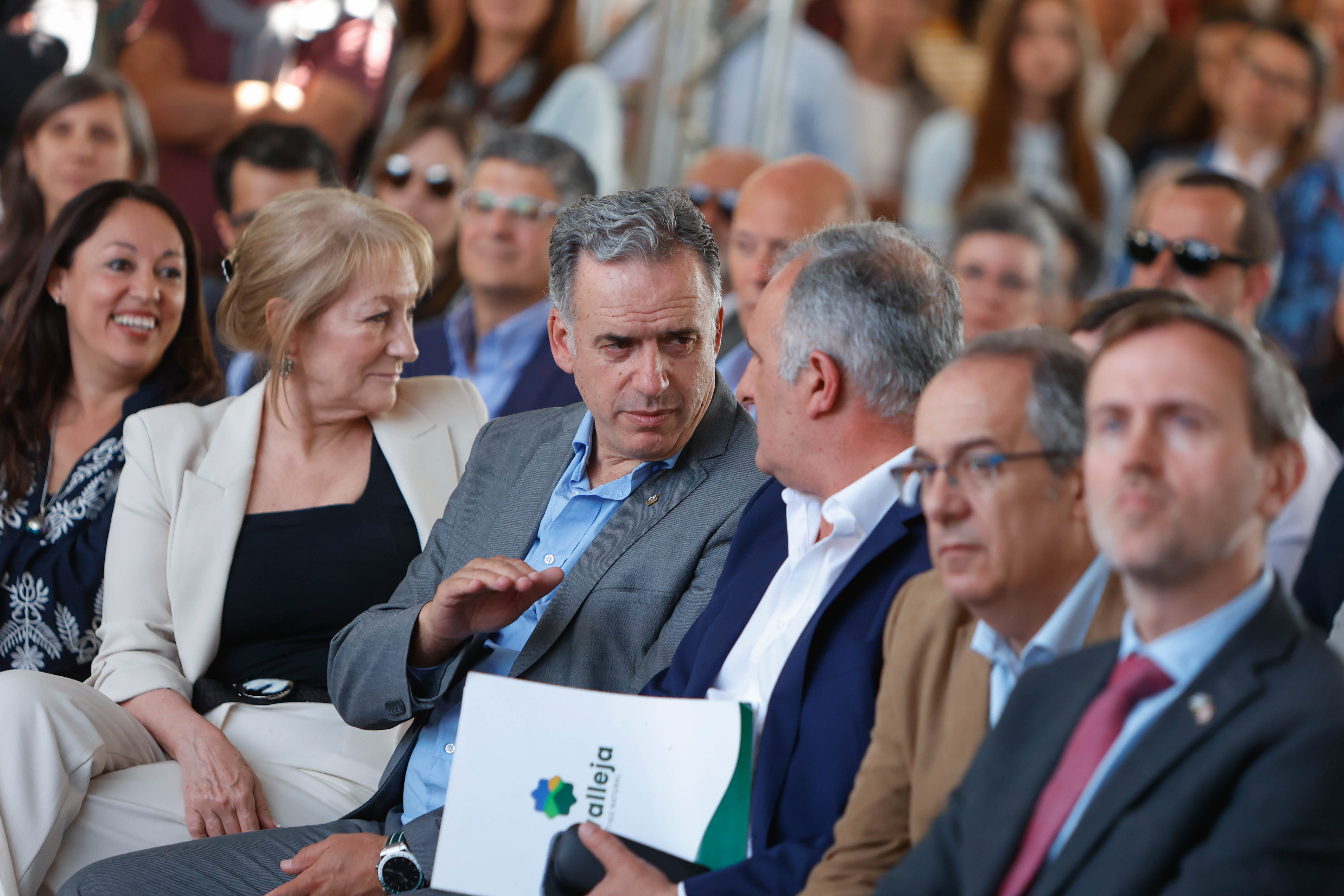Orsi, sentado en primera fila de la platea, dialoga con el intendente de Lavalleja rodeado de otras autoridades.