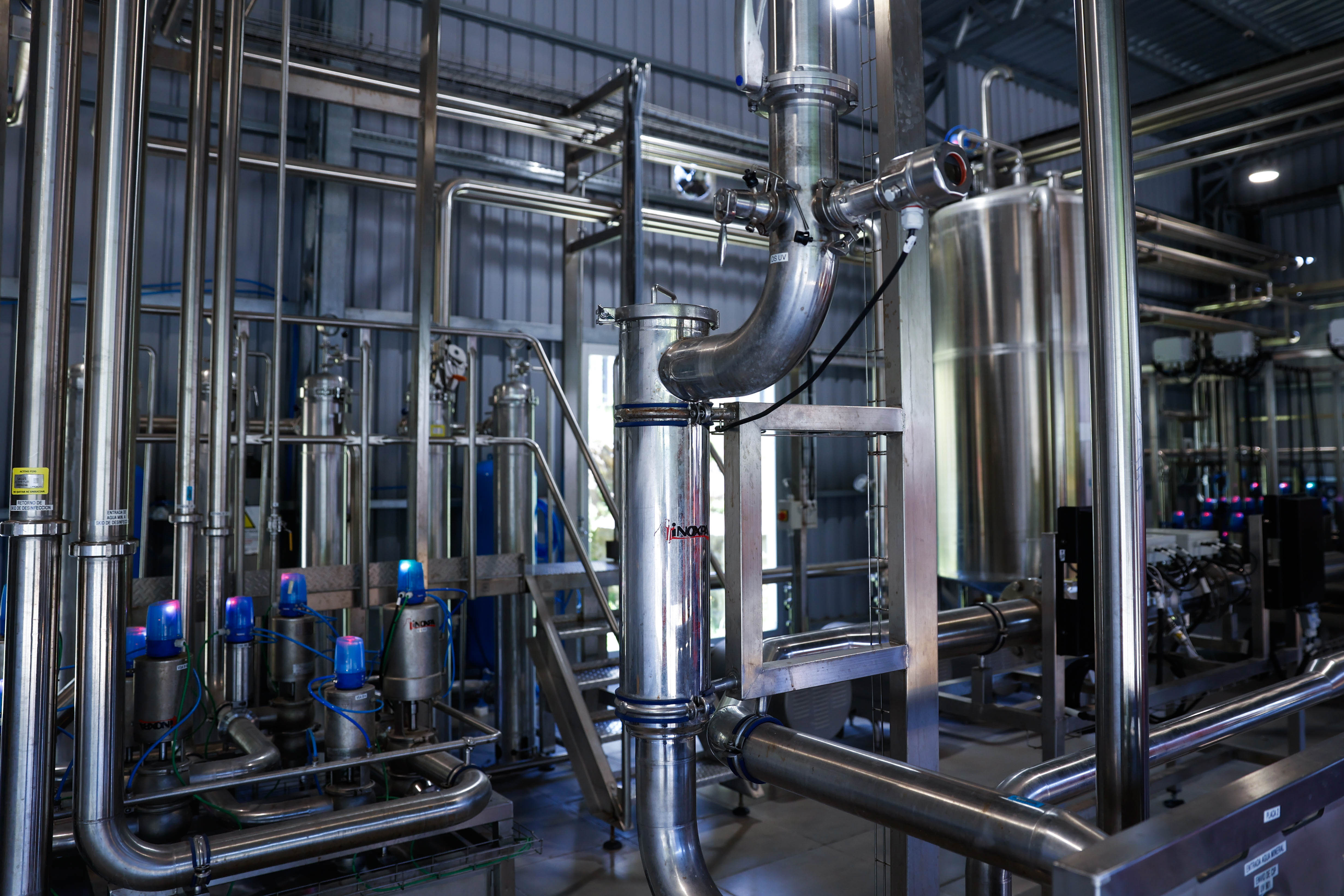 Primer plano del sistema de tuberías, tanques y maquinaria de acero inoxidable en la planta de Salus.