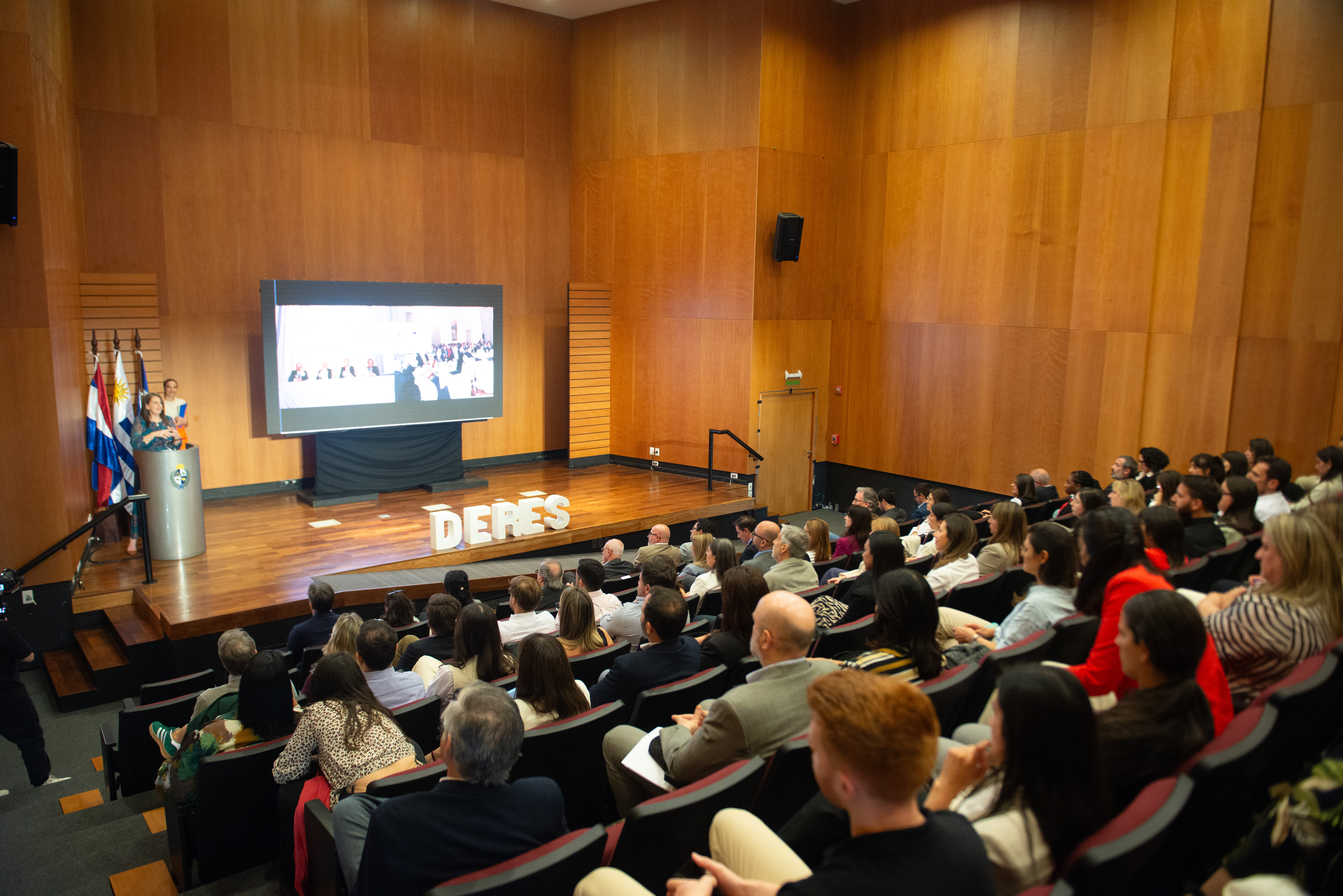 Plano general del auditorio de Presidencia con el público sentado en la platea mirando hacia el escenario donde las autoridades disertan.