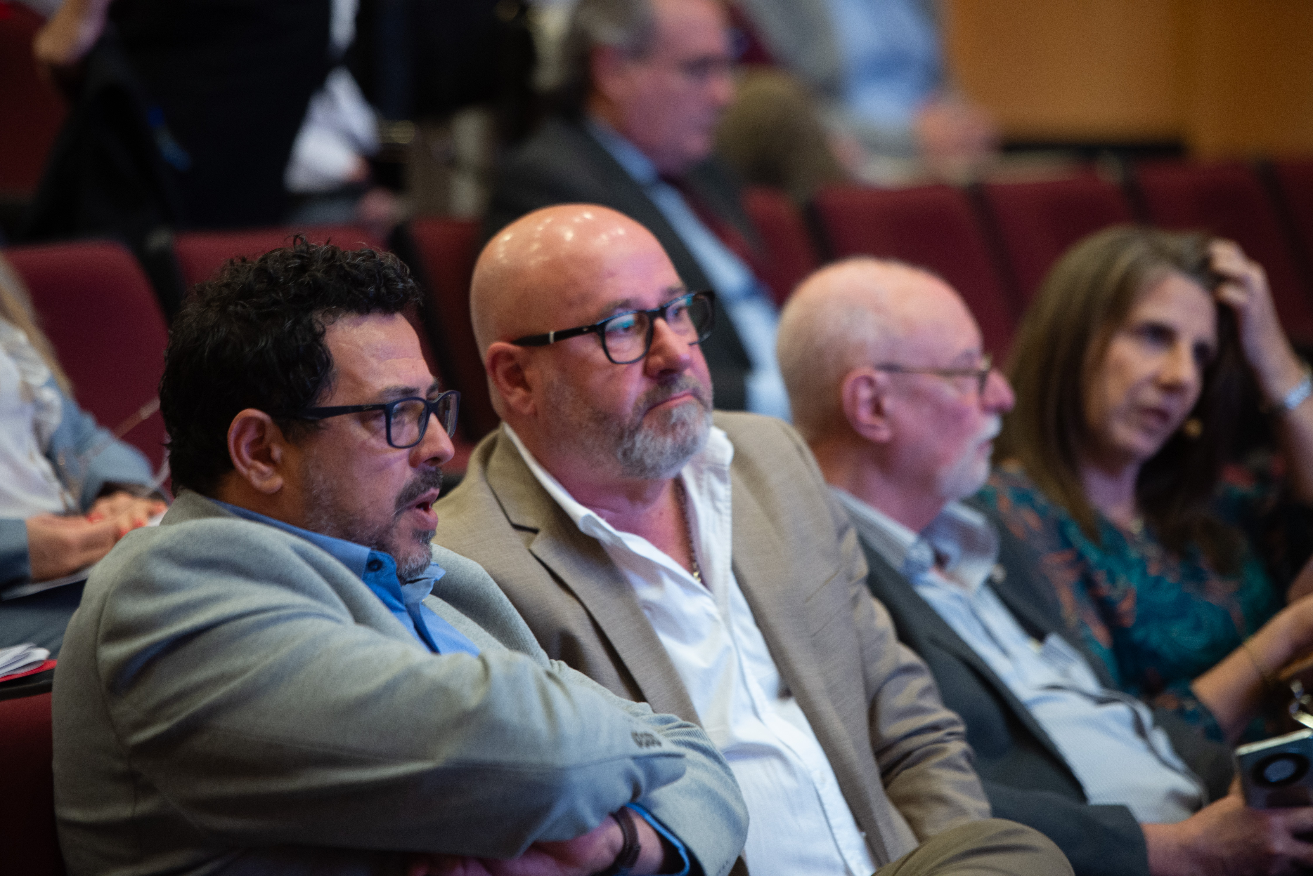 Secretario de Presidencia dialoga con un hombre sentado en la primera fila del auditorio.