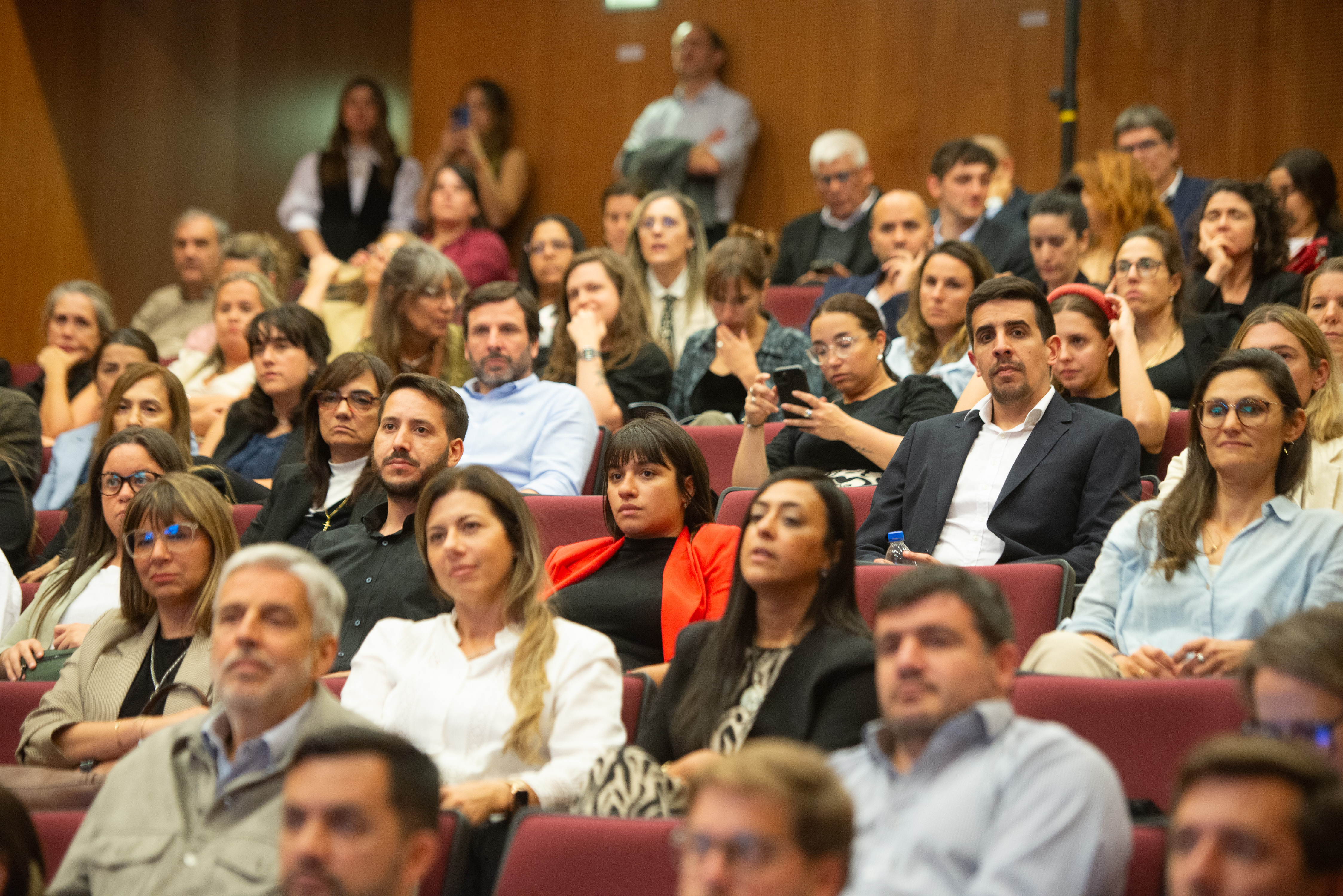 Plano general del público sentado en la platea del auditorio mirando hacia el escenario.