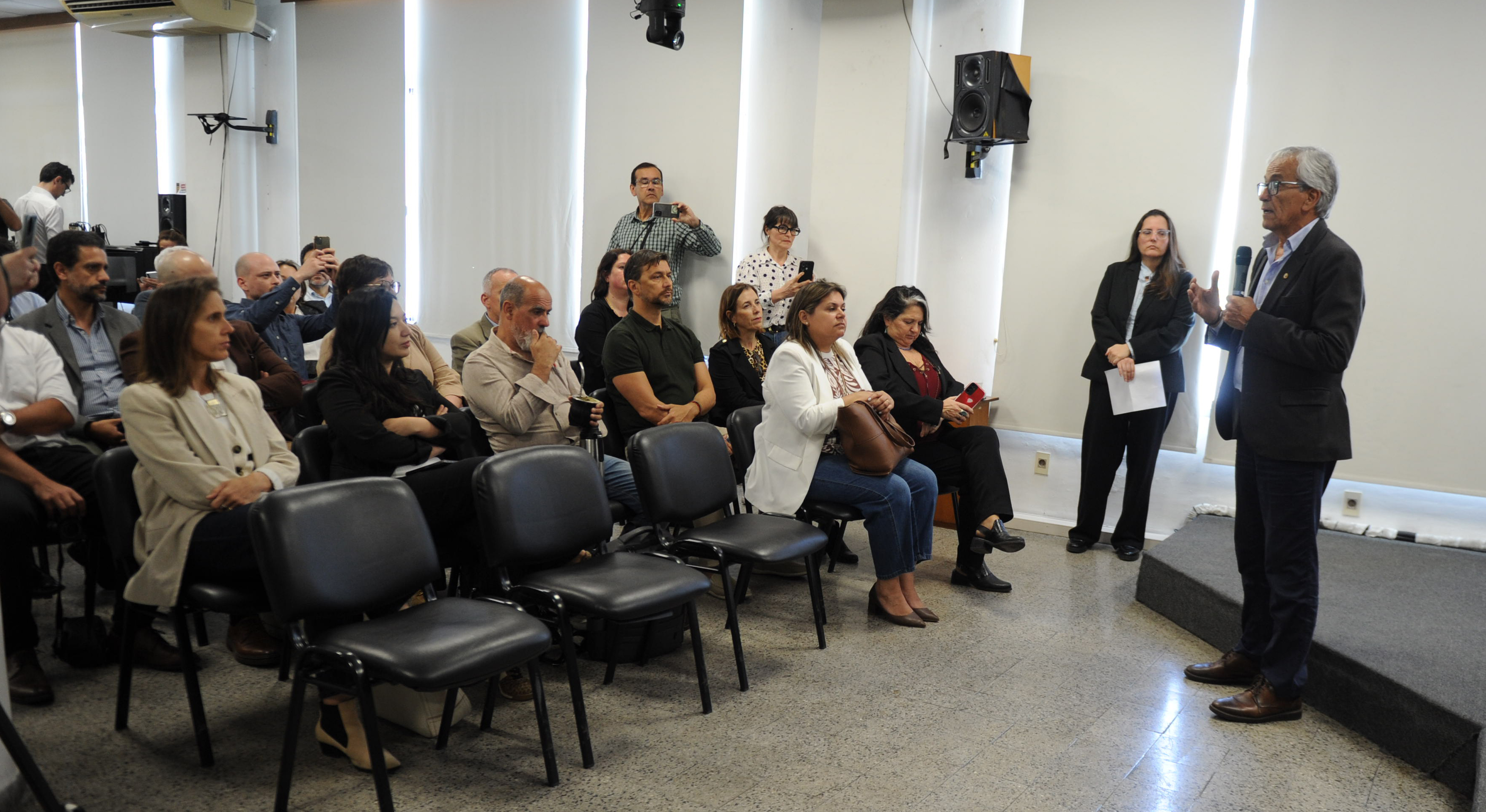 Ministro de Trabajo diserta de pie con micrófono en mano mientras el público sentado en sillas lo escucha atentamente.