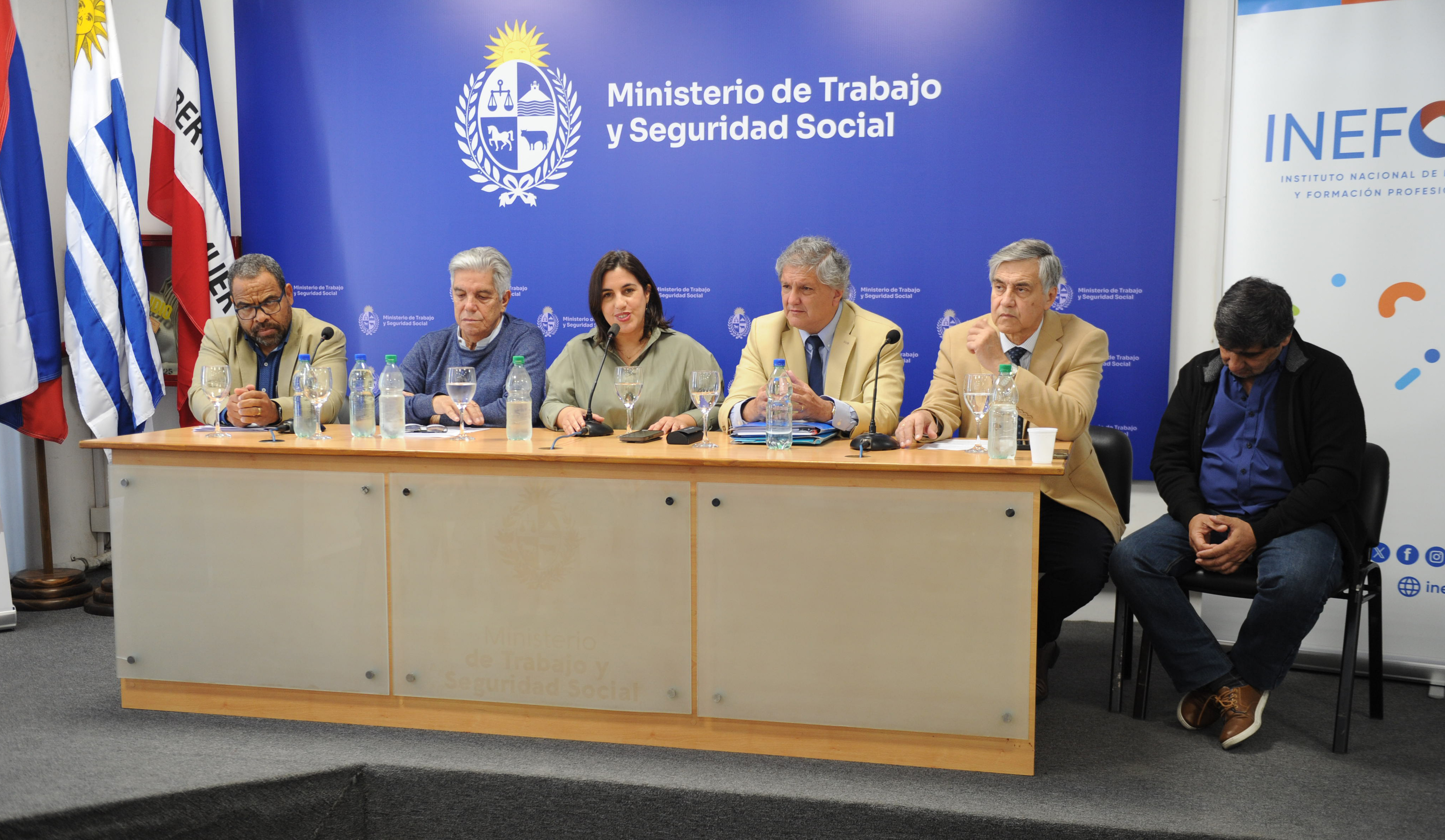 Autoridades del Ministerio de Trabajo y de los trabajadores y empleadores del rubro sentadas en mesa con micrófono para disertar.