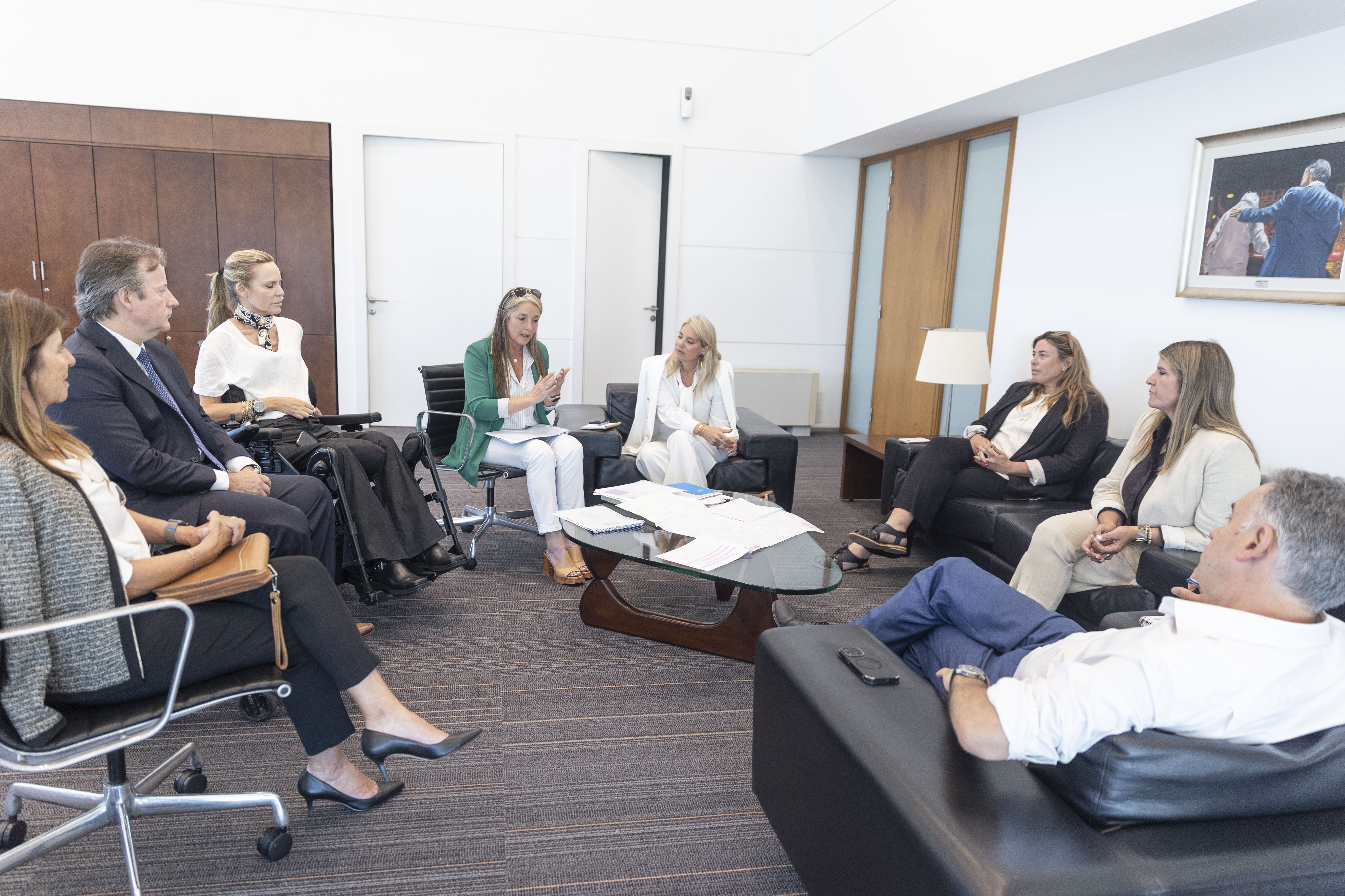 Otra perspectiva de Orsi conversando con los representantes de las fundaciones sentado en círculo en la sala de reuniones. 